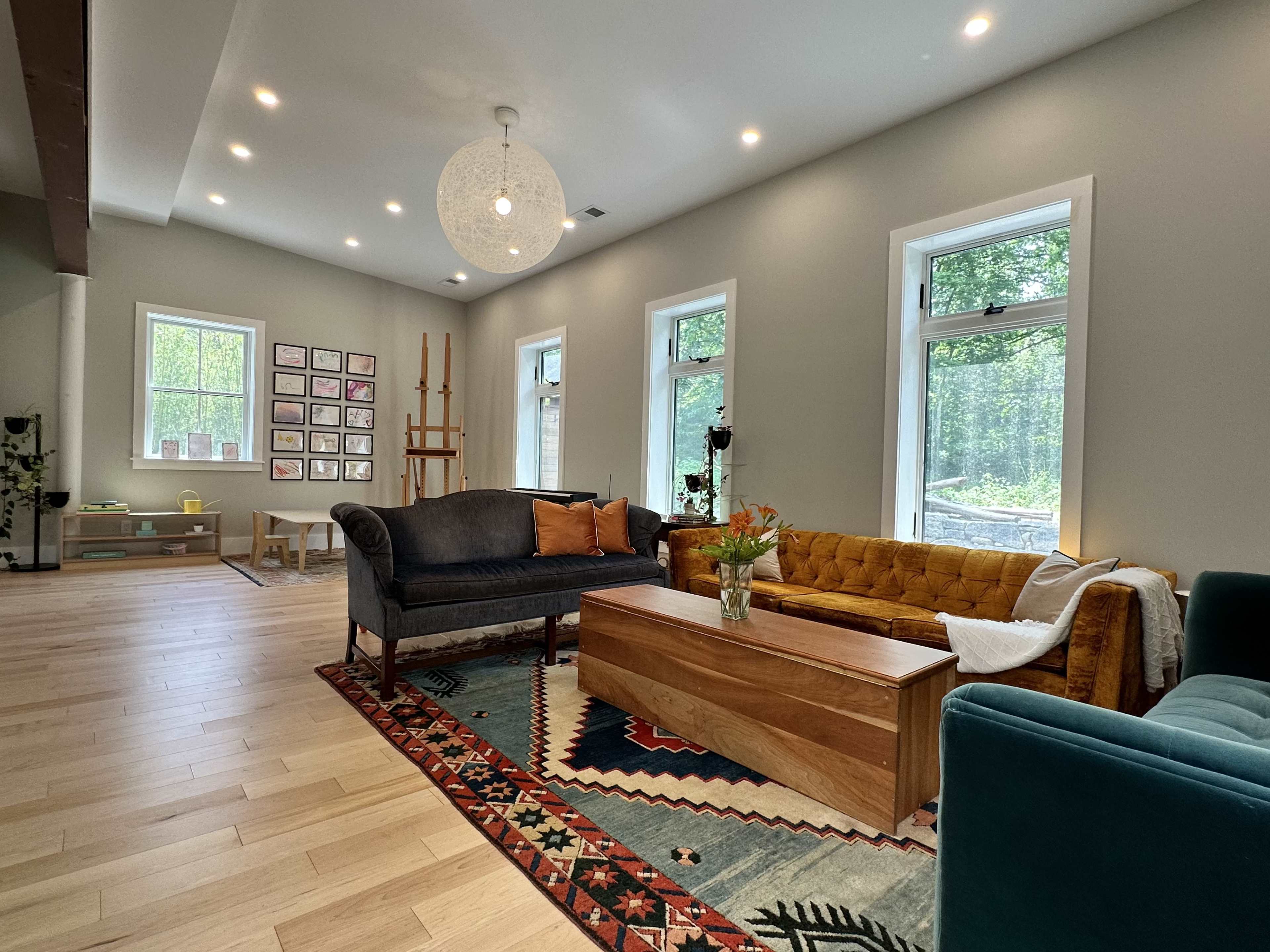 The room features a mix of seating options, including a green couch and a yellow tufted sofa, arranged around a wooden coffee table on a patterned rug.