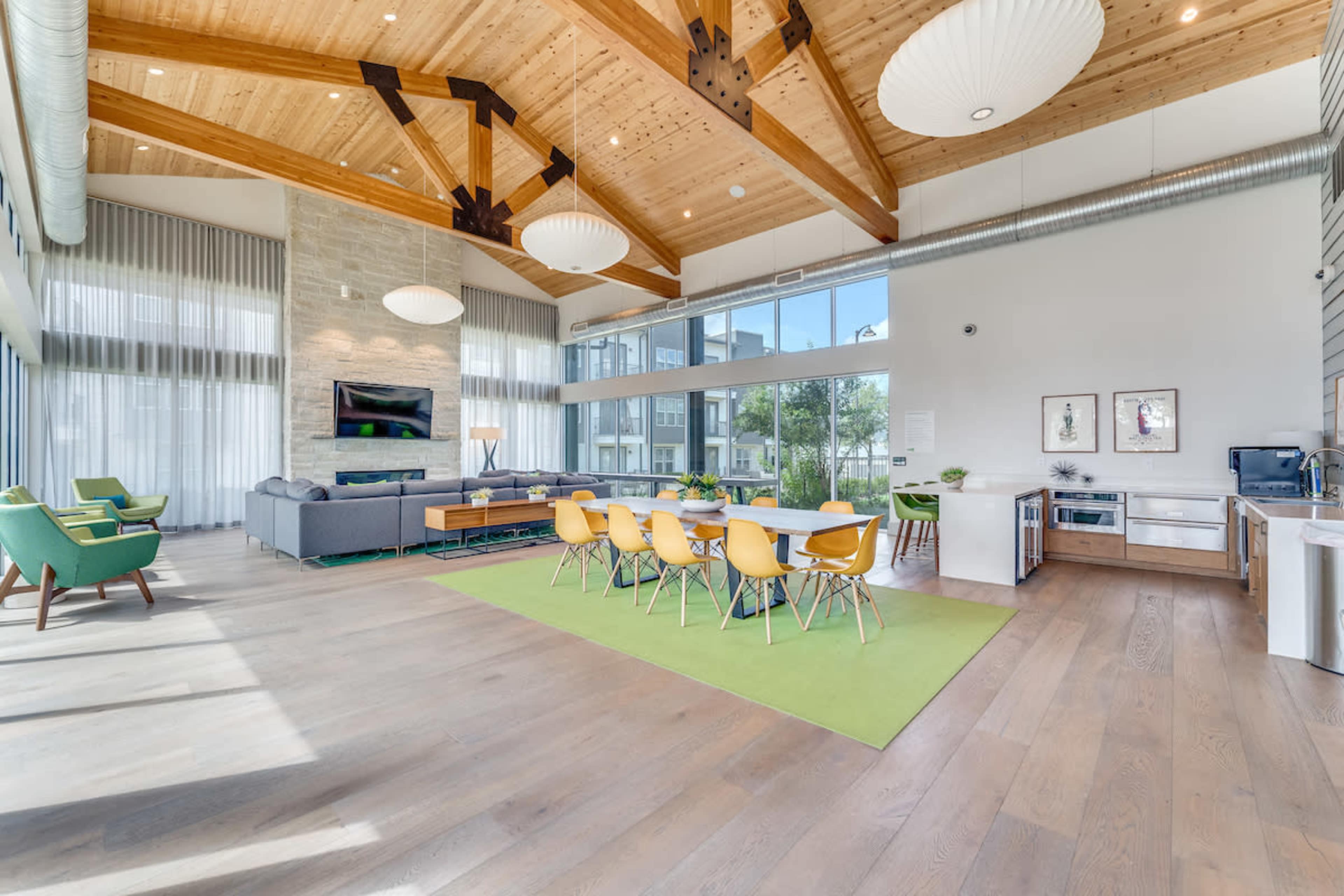 A spacious common area with a dining table, kitchen appliances, and large windows allowing natural light to fill the room.