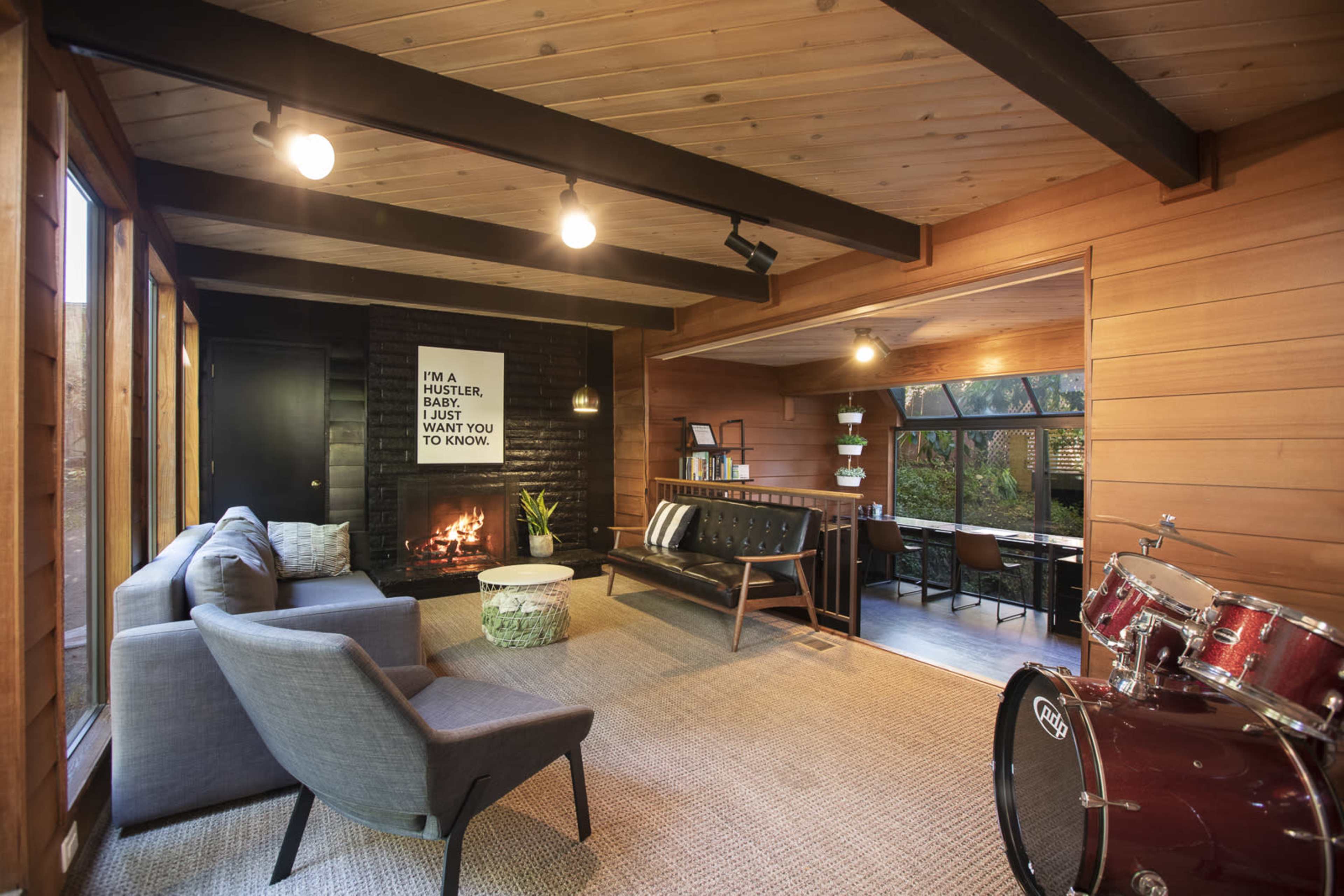 A living room with a fireplace, modern furniture, and a dining area visible through large windows.