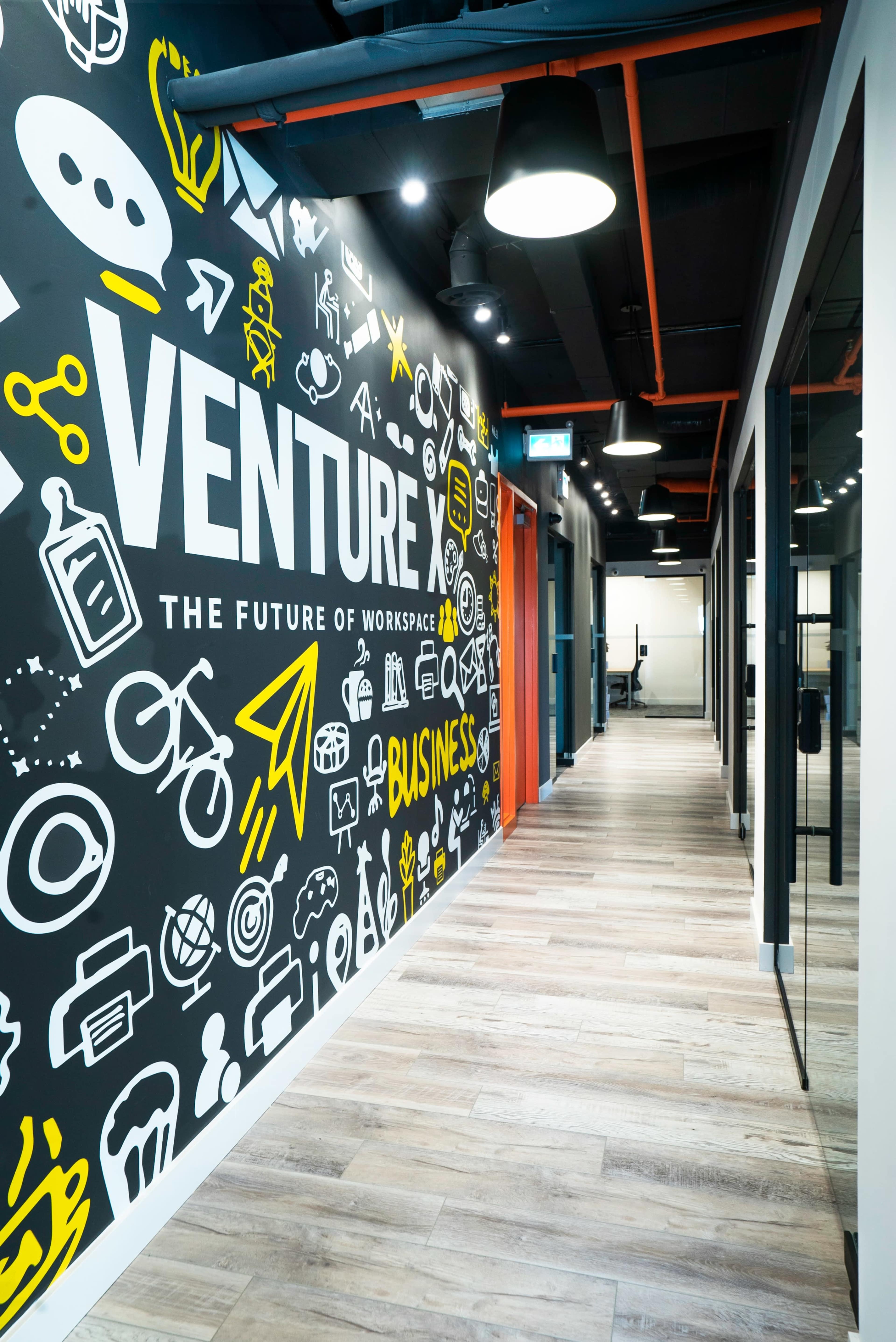 The image shows a modern office hallway with a vibrant mural featuring various business-related graphics on one wall.