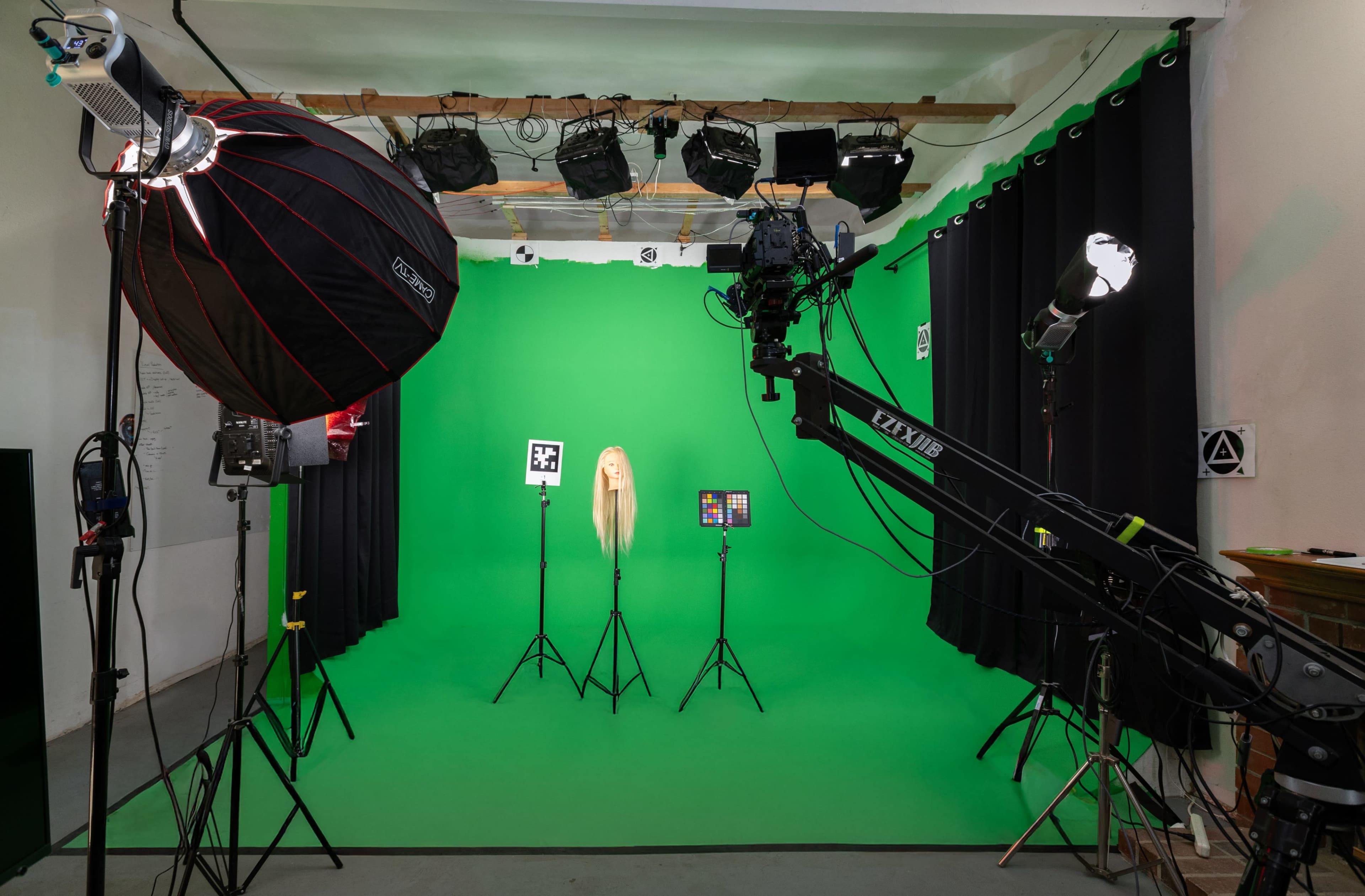 The image shows a green screen studio setup with multiple lighting sources and a mannequin displaying long hair at the center.