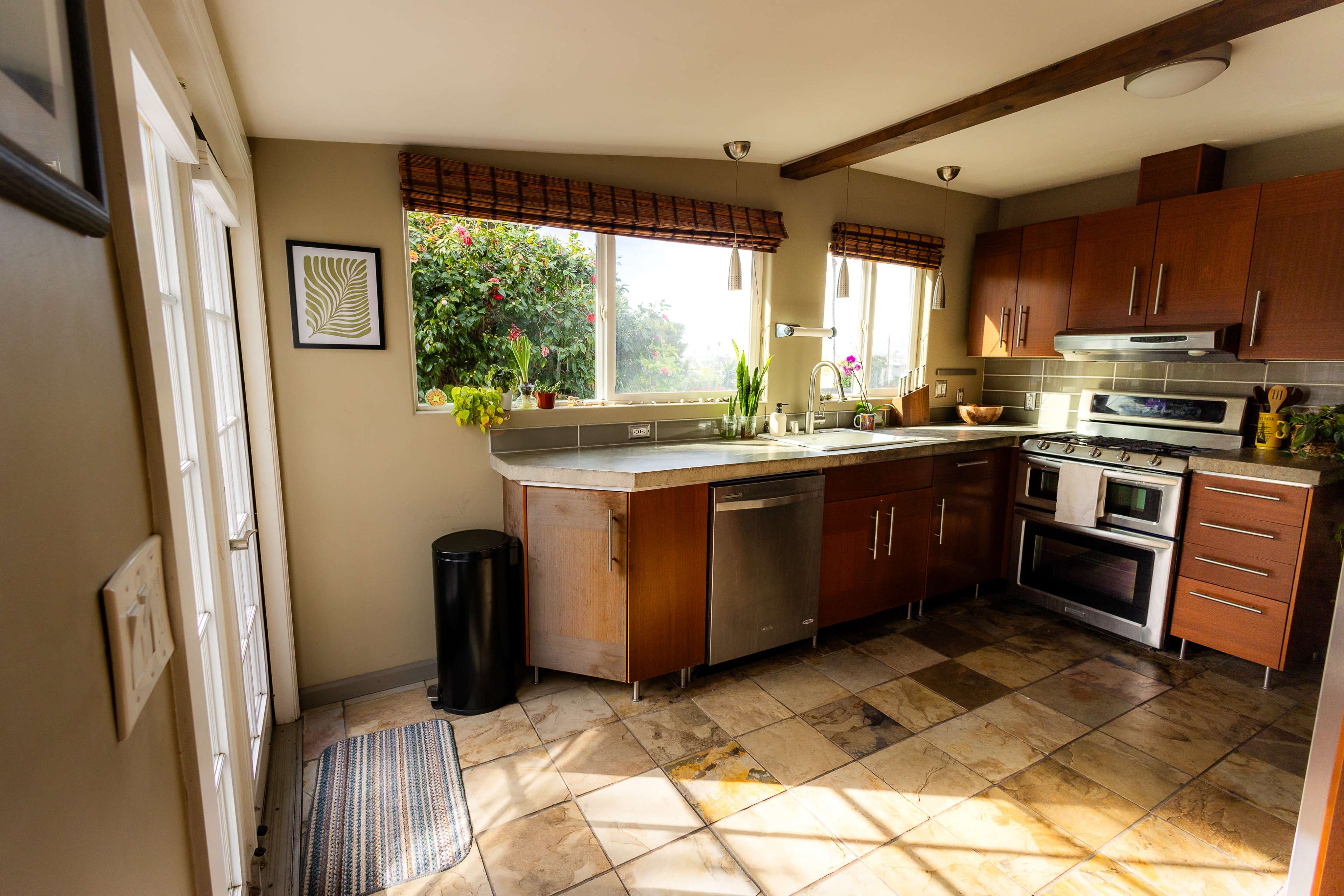 A kitchen features wooden cabinetry, modern appliances, and ample natural light from large windows.