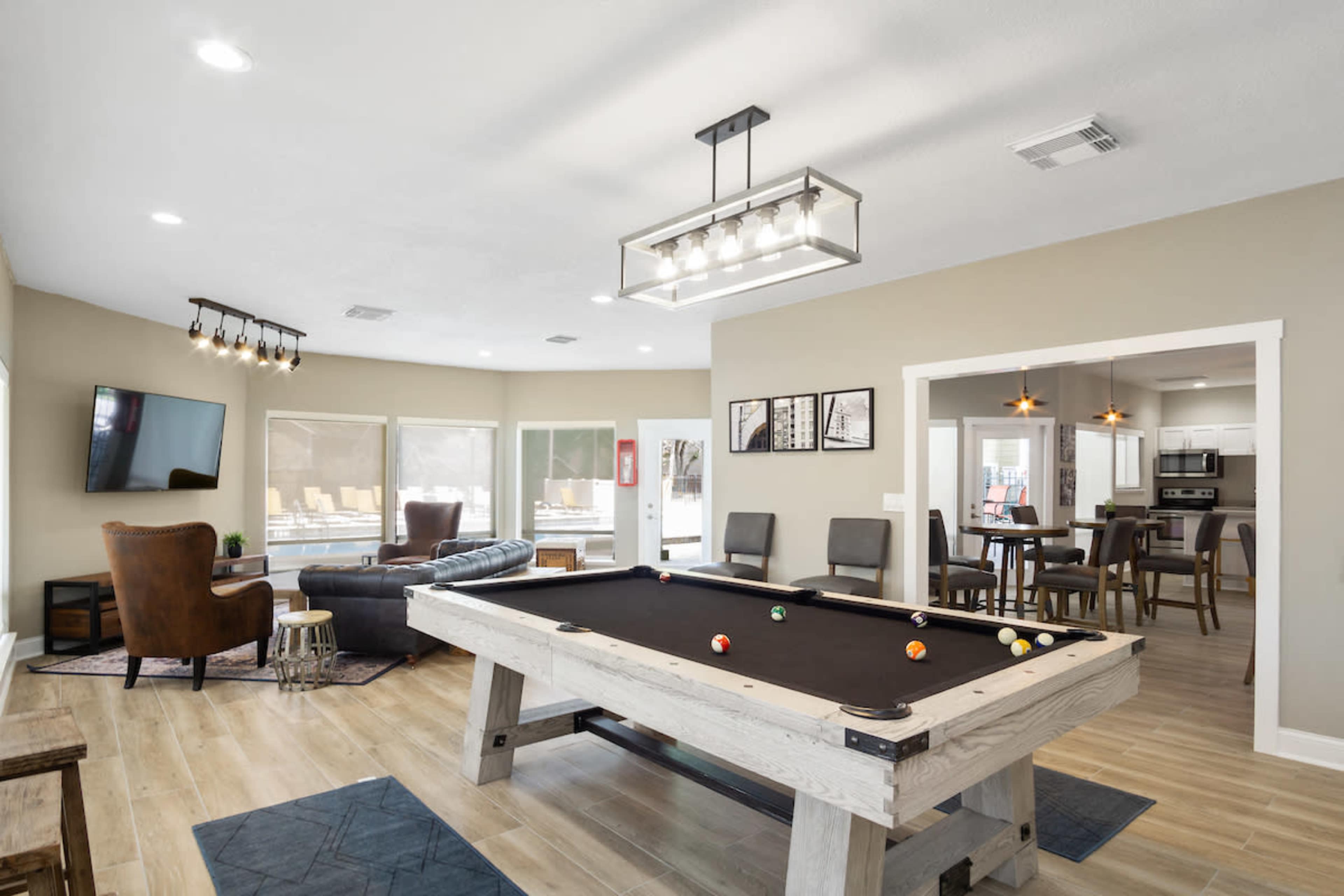 A spacious living area featuring a pool table, a sectional sofa, a television, and a dining area in an open floor plan.