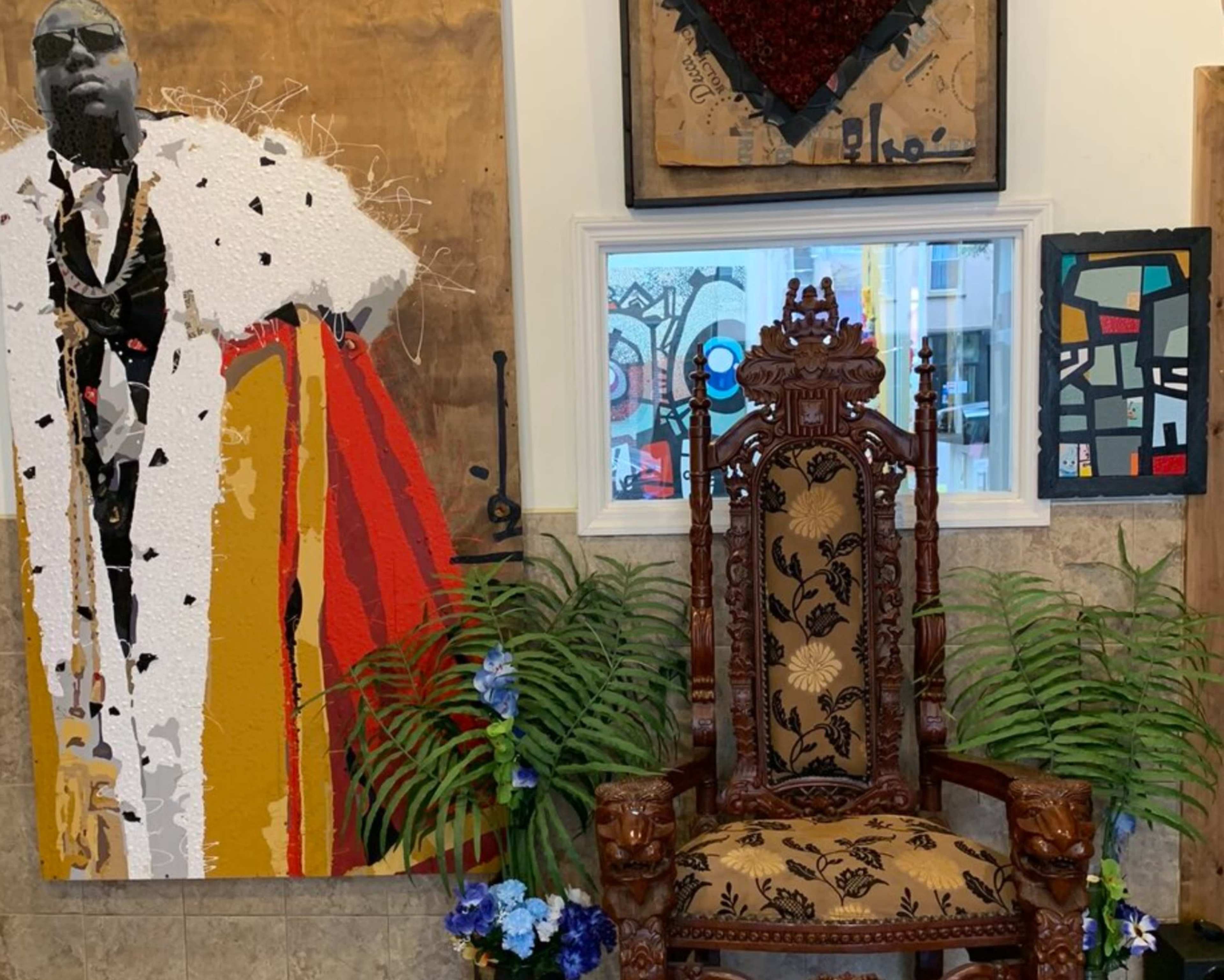 An ornate wooden chair positioned beside a large, colorful artwork of a figure in a fur coat, with various plants and smaller artworks in the background.