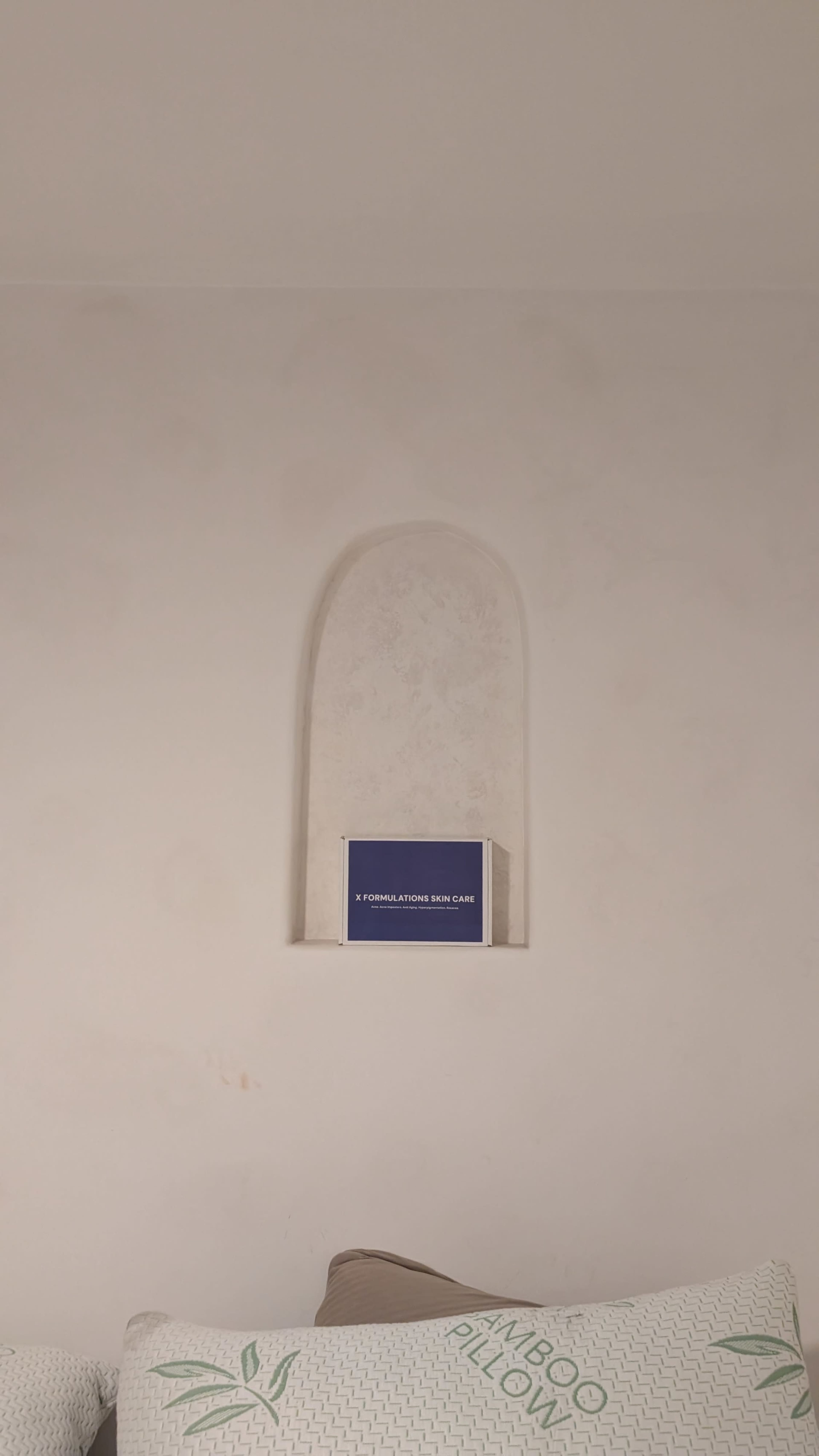 A blue box is placed on a small shelf set into a beige wall.