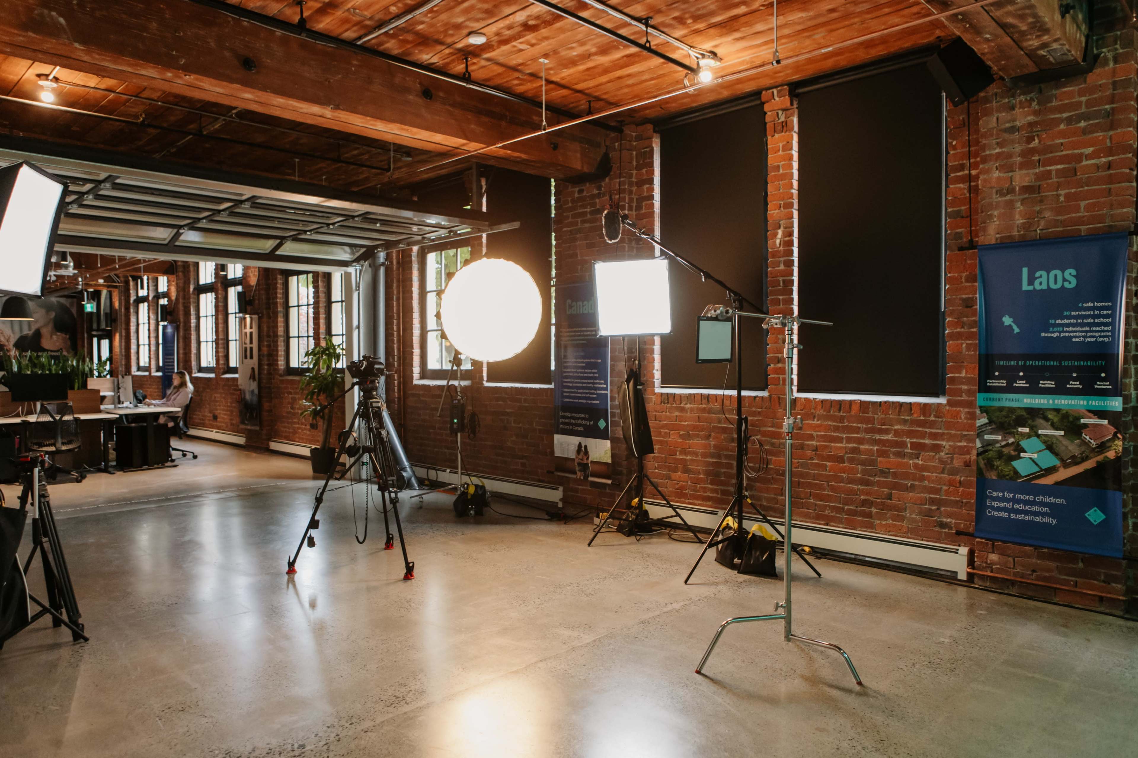 A spacious studio with brick walls, equipped with lighting equipment and cameras, ready for a photoshoot or video production.