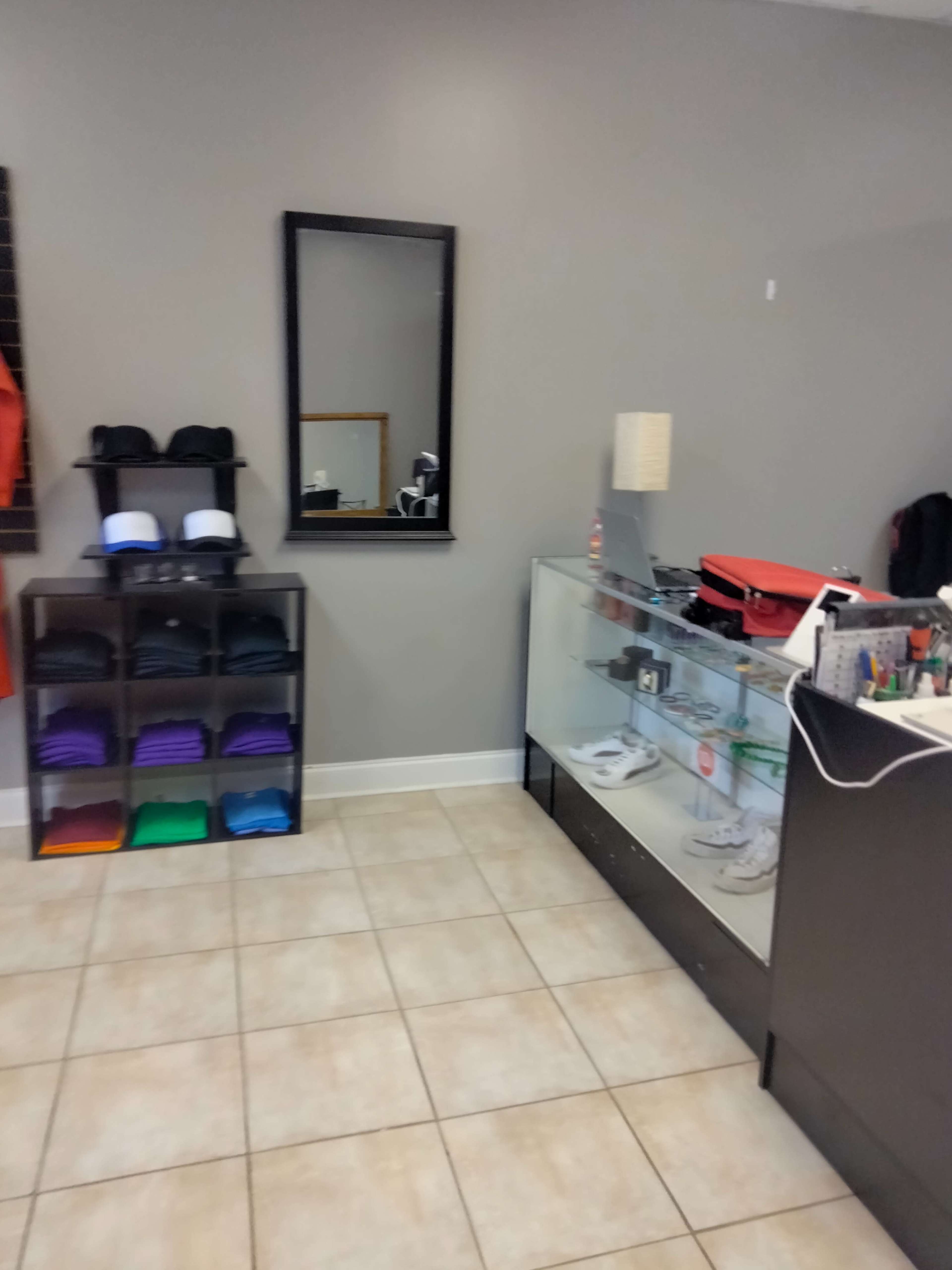 A retail space with a display case and a shelf of folded clothing items, along with a mirror on the wall.