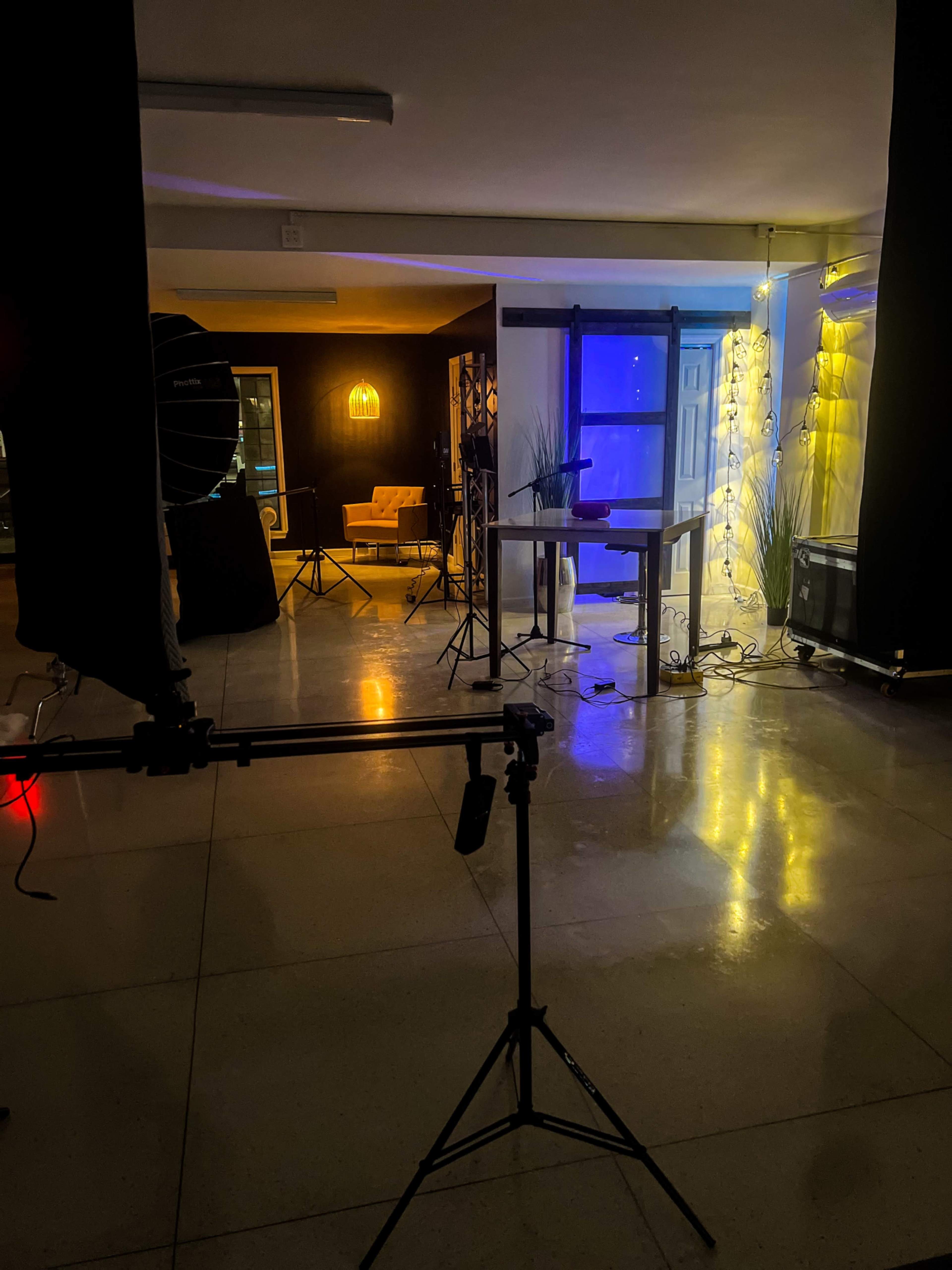 A dimly lit studio space featuring various lighting equipment and a backdrop.