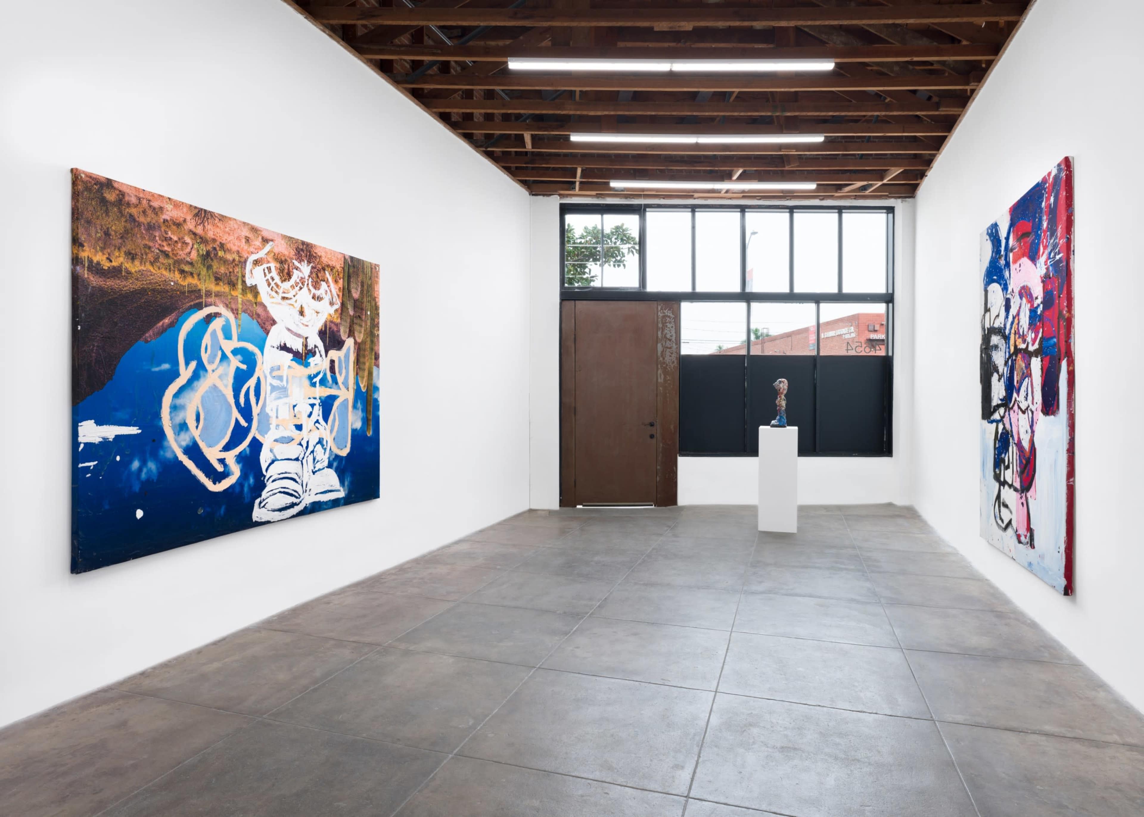 The image shows a contemporary art gallery featuring two large paintings on the walls and a sculpture on a pedestal.