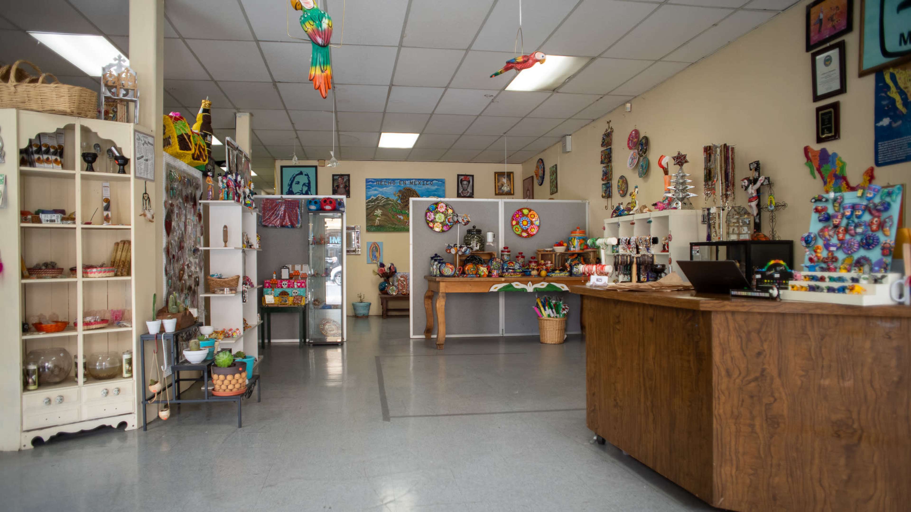 A colorful gift shop with various handmade items displayed on shelves and a wooden counter at the front.