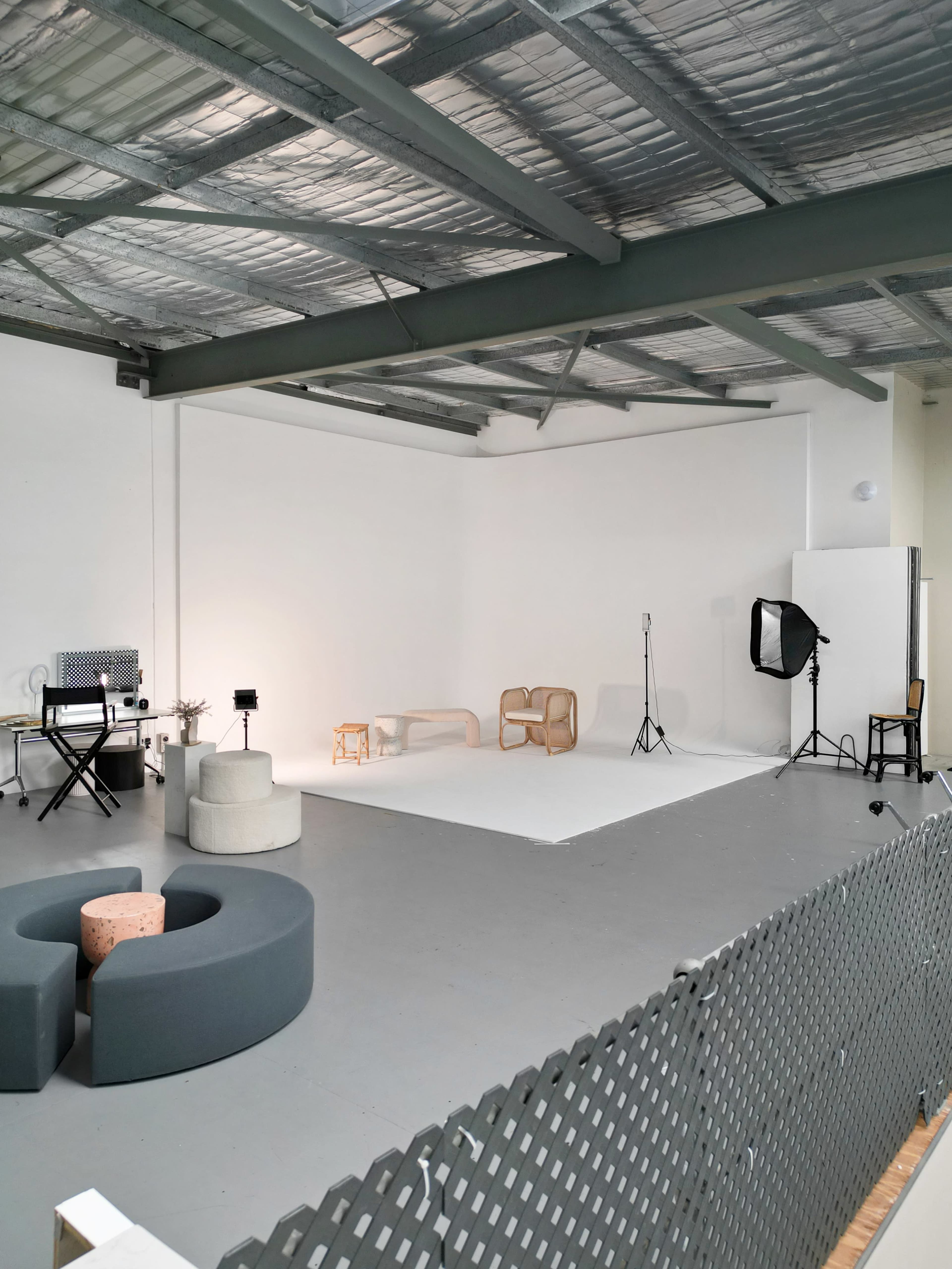 A spacious photography studio featuring various pieces of furniture, a backdrop, and lighting equipment.