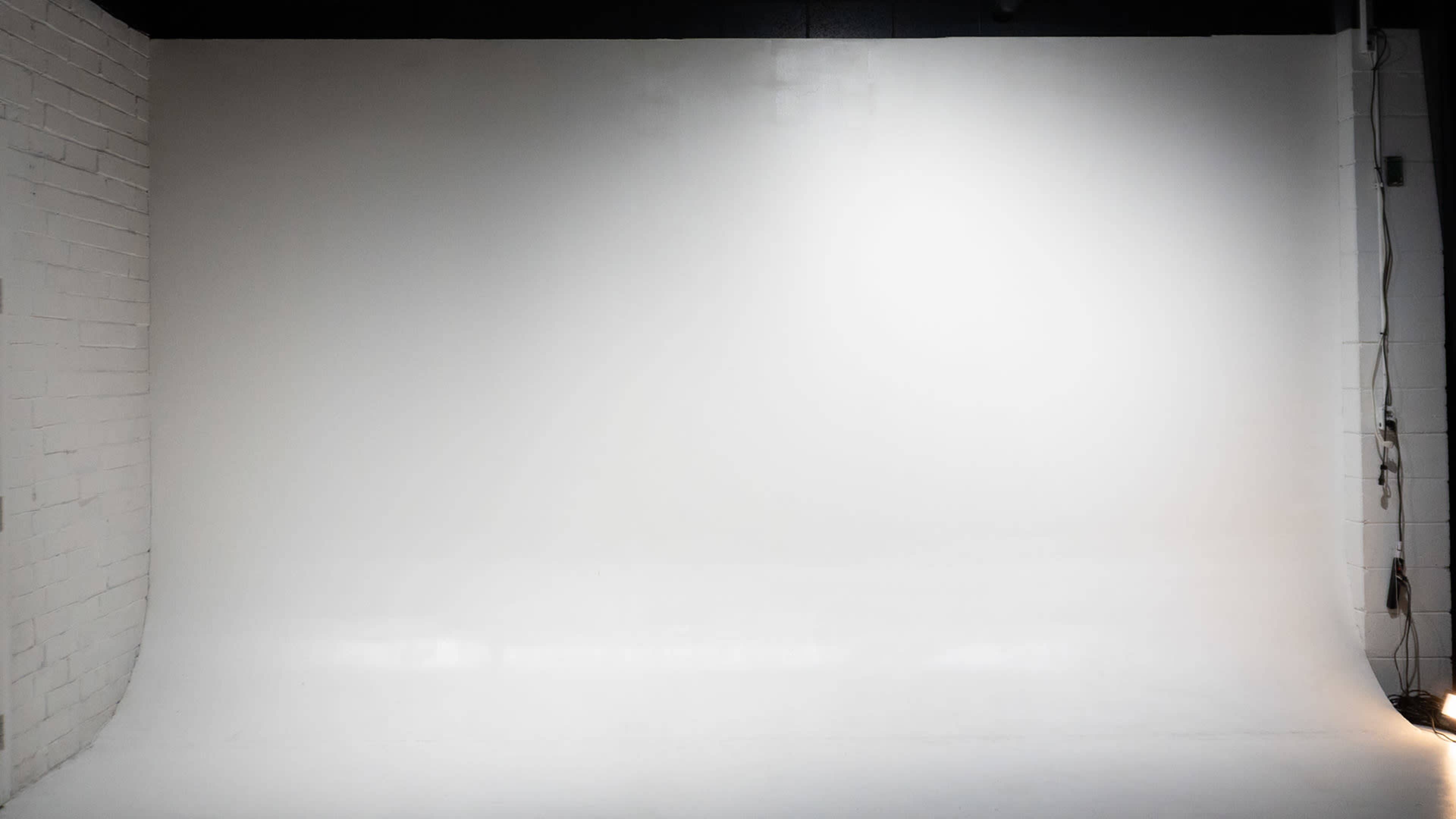The image shows a plain white studio backdrop with smooth flooring and walls.