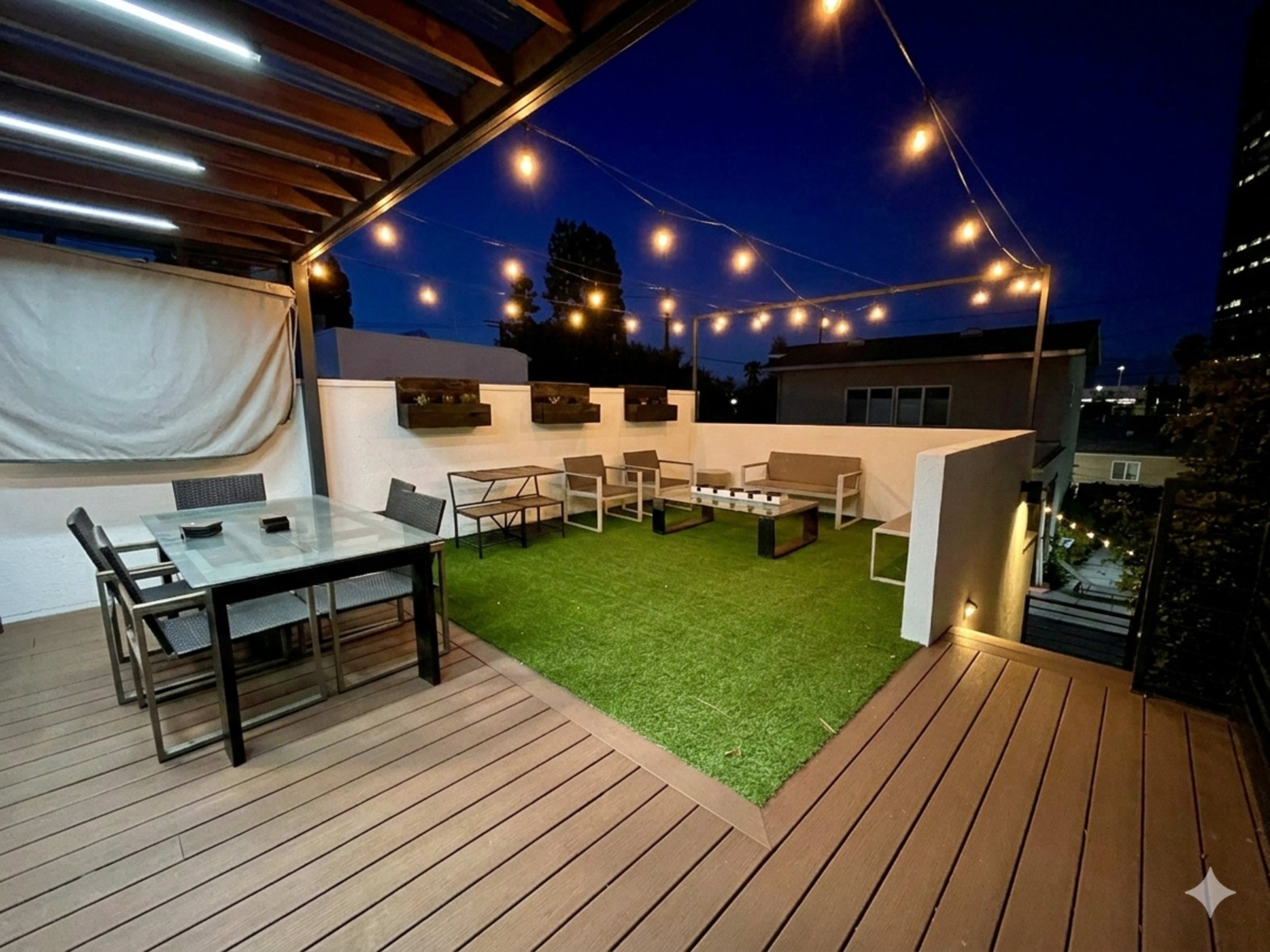 A well-lit rooftop patio features seating areas and string lights, creating a relaxed outdoor ambiance at night.