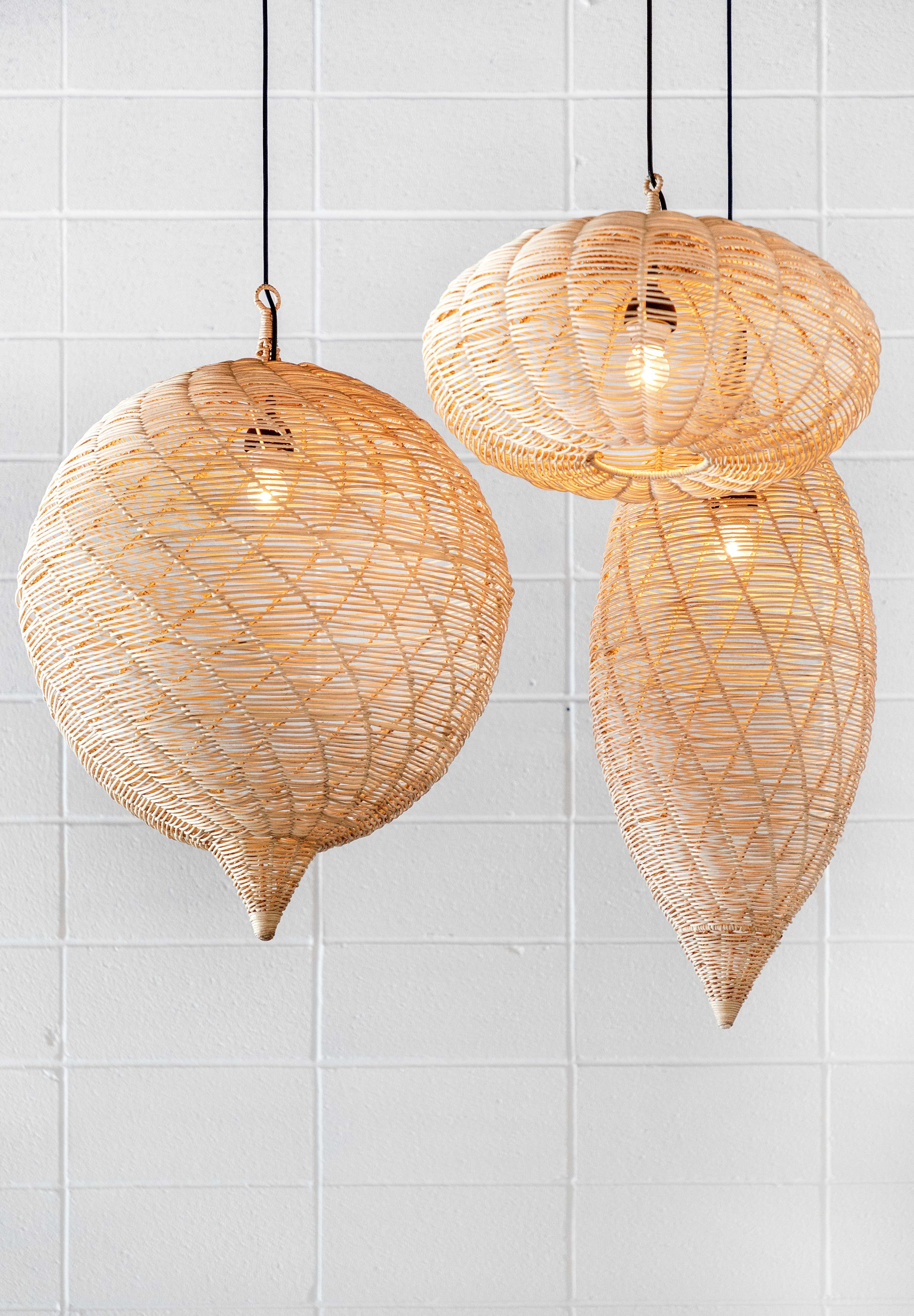 Three woven pendant lights hang from the ceiling against a white wall.