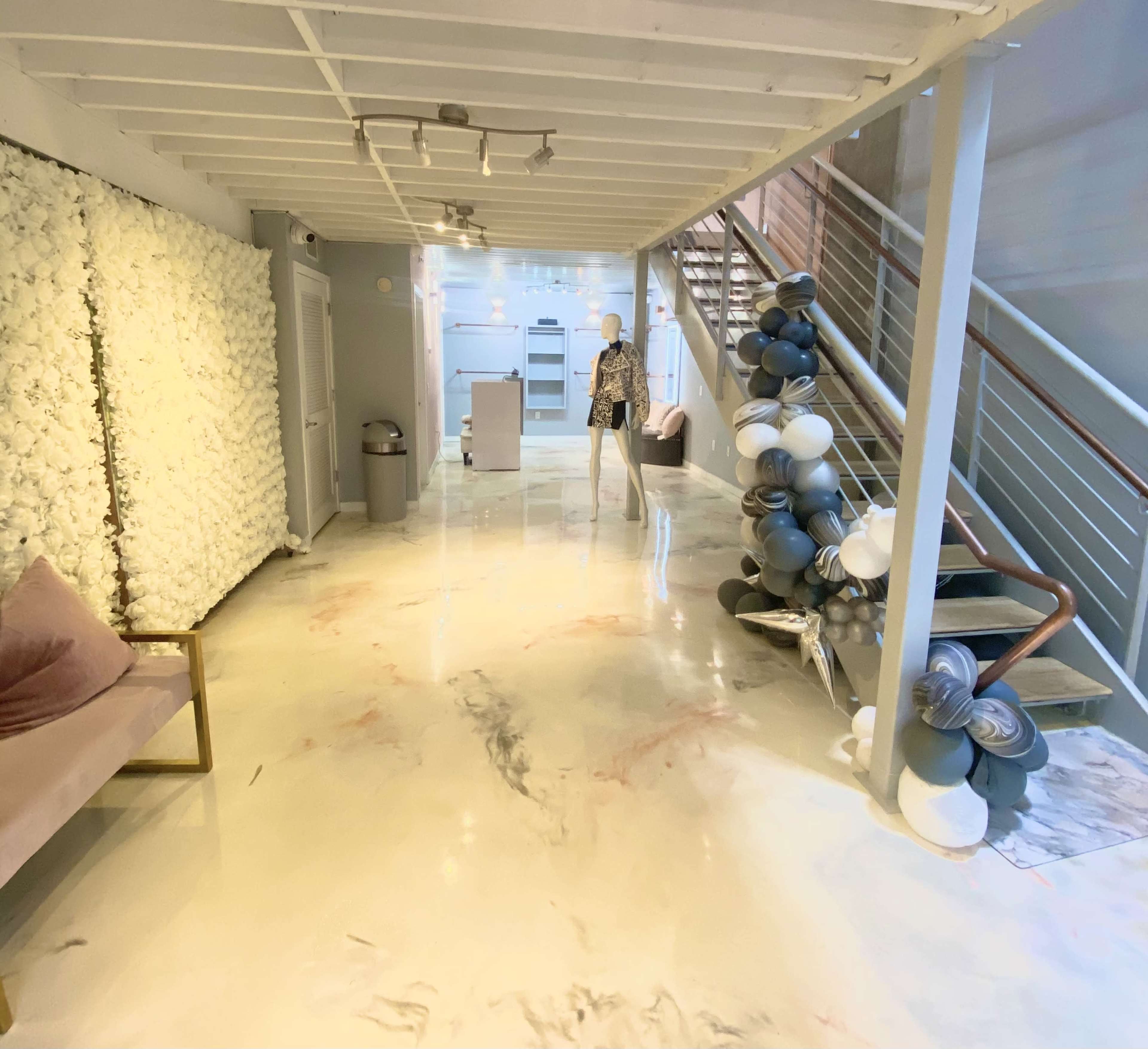 A modern interior space featuring a staircase, a mannequin on display, a seating area, and a decorative wall with white textures.