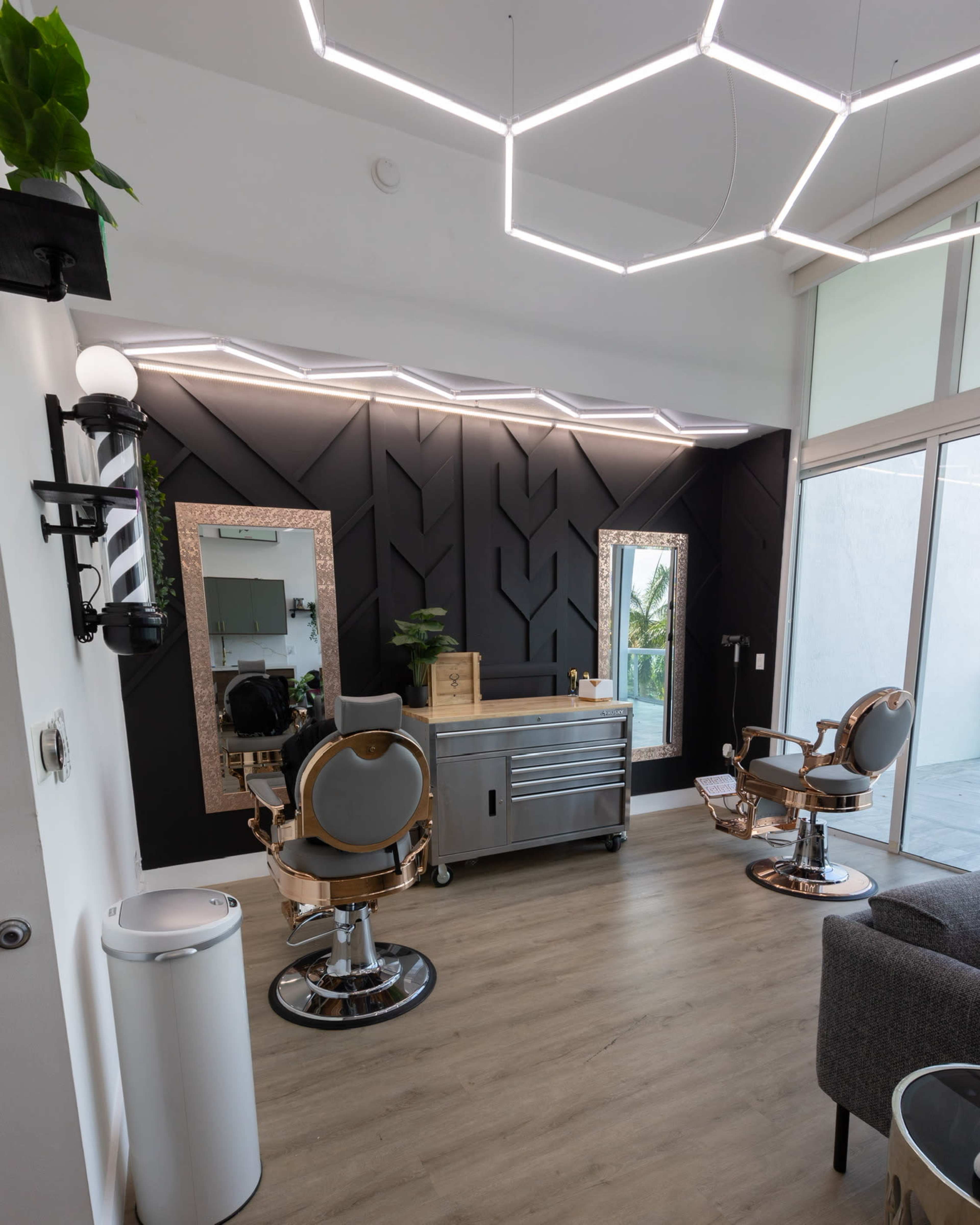 A modern hair salon interior featuring two mirrored styling stations, a silver styling cart, and contemporary light fixtures.