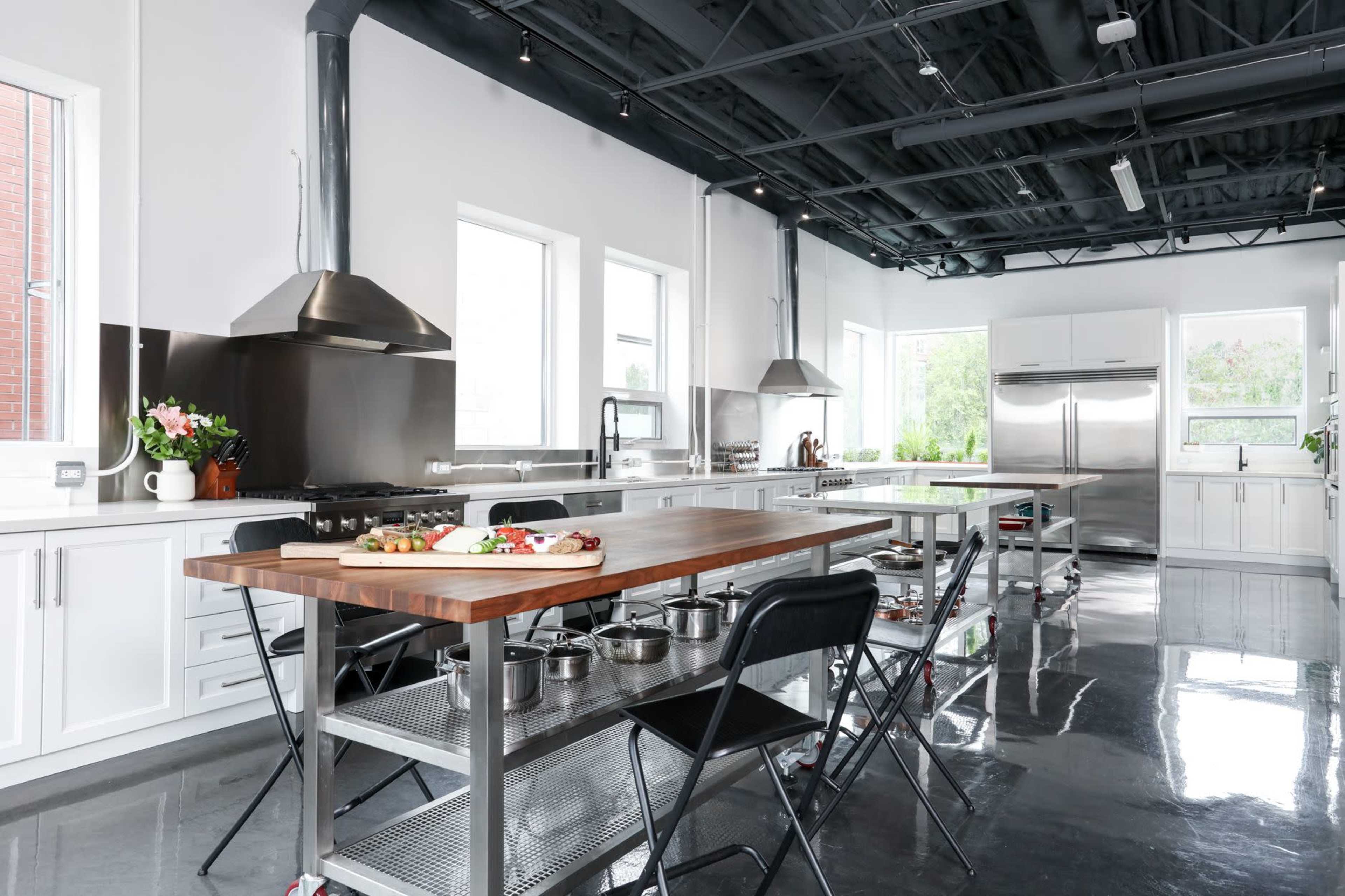 A modern kitchen with stainless steel appliances, a large wooden island, and sleek cabinetry.