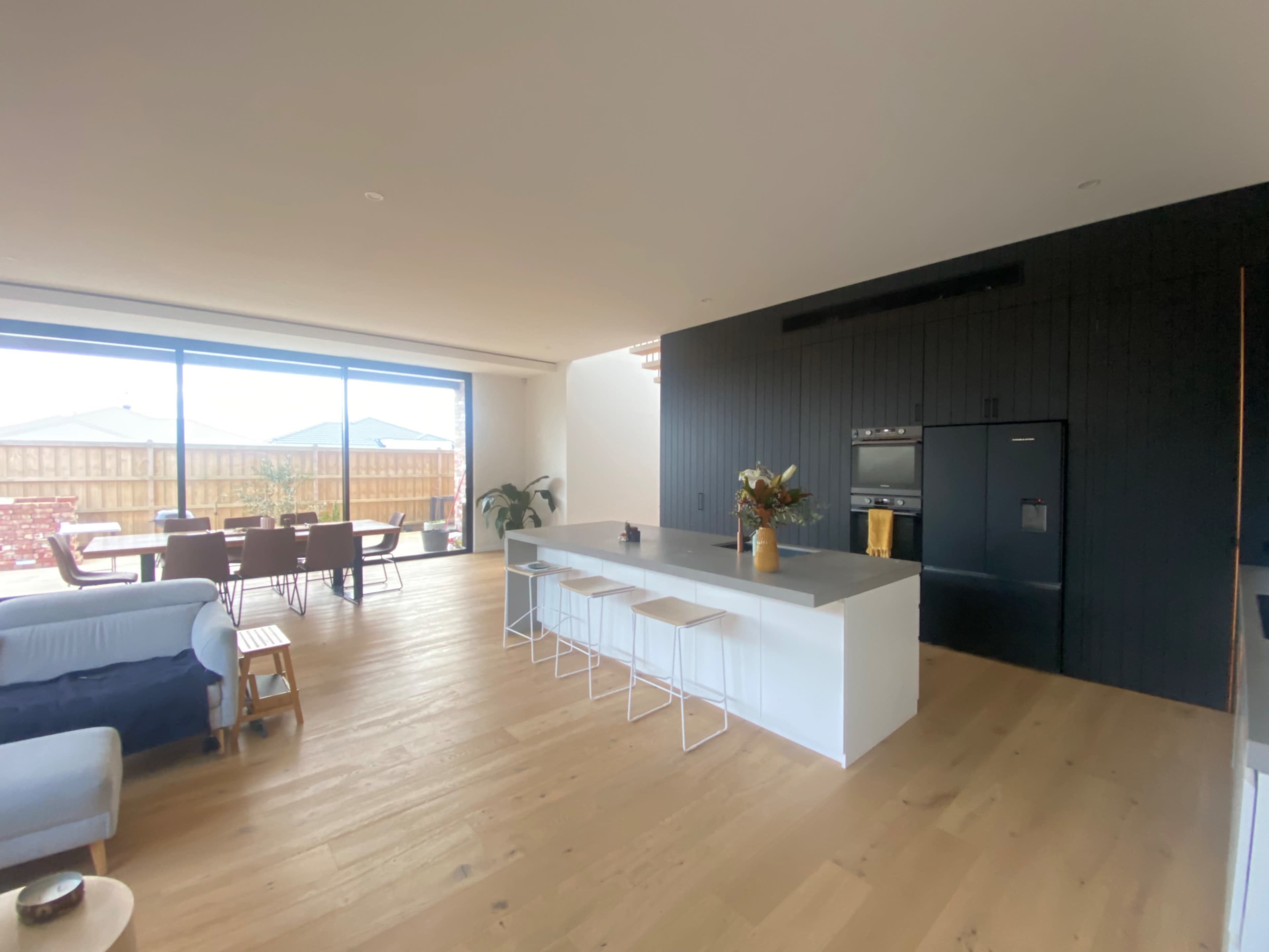 A modern open-plan living space that includes a kitchen with a large island, seating, and a dining area with a table in view.