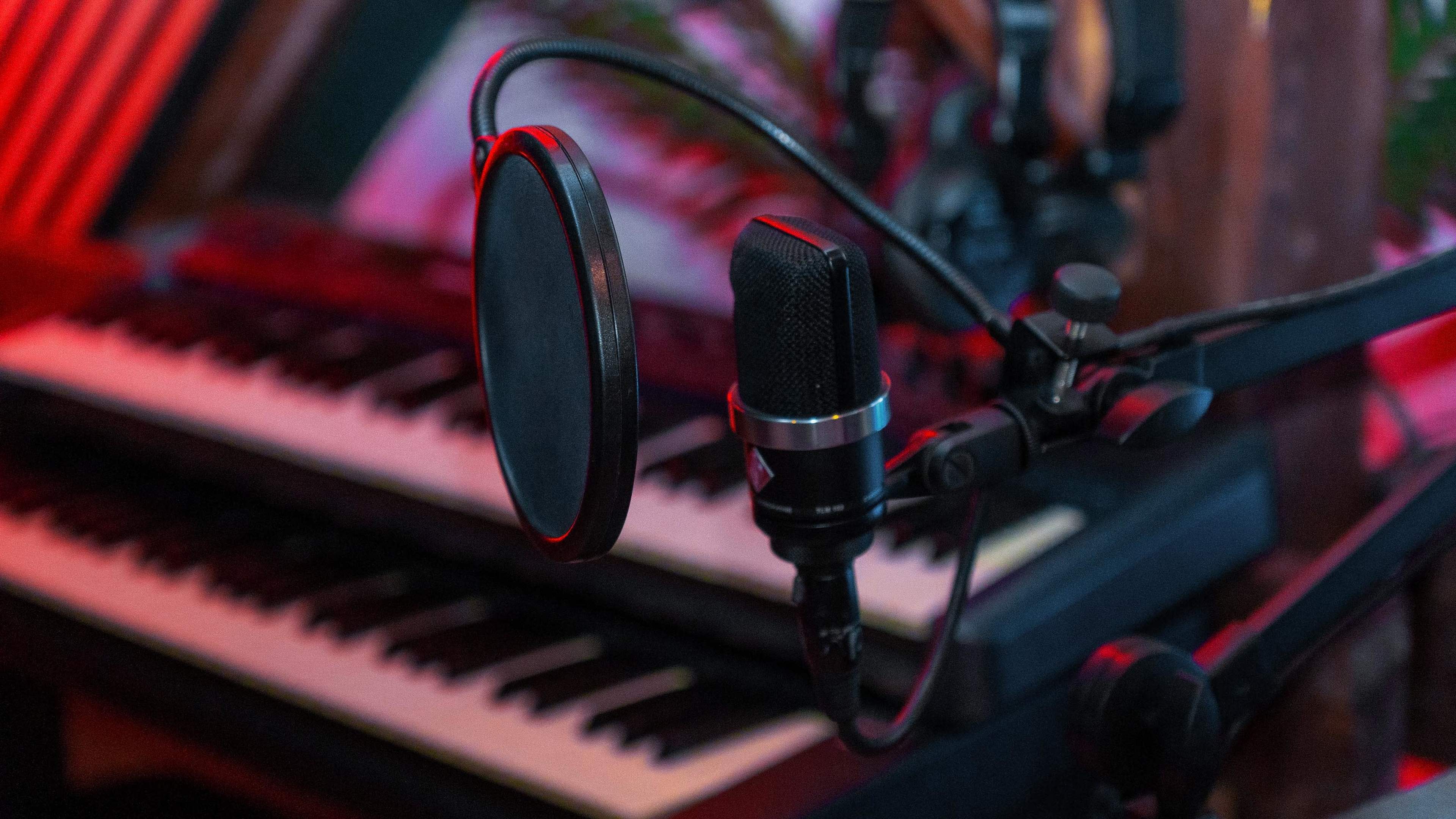 A microphone with a pop filter is positioned in front of a keyboard.
