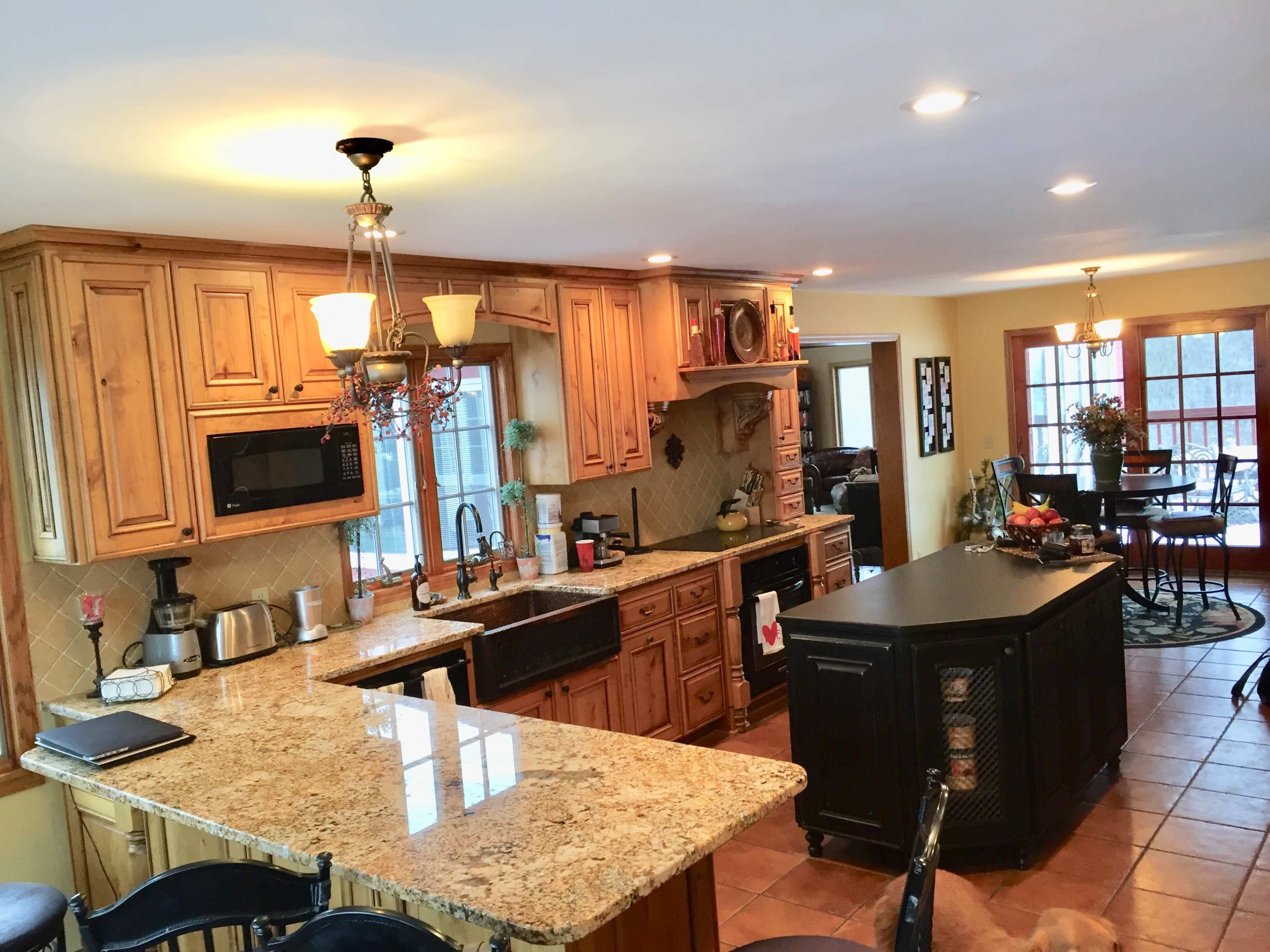 The kitchen features wooden cabinetry, granite countertops, and a central island with seating.