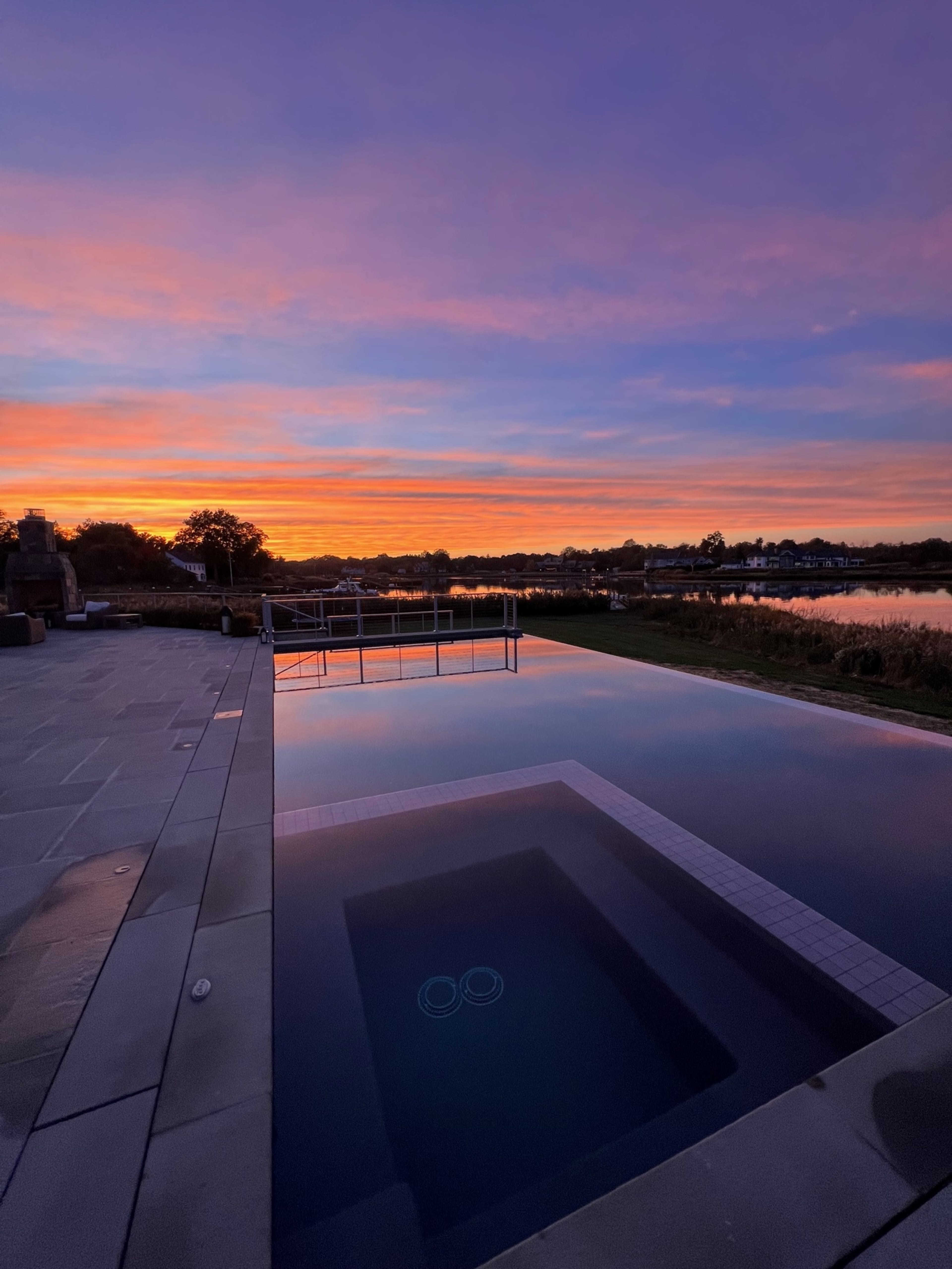 A swimming pool at sunset, with vibrant colors reflected in the water.