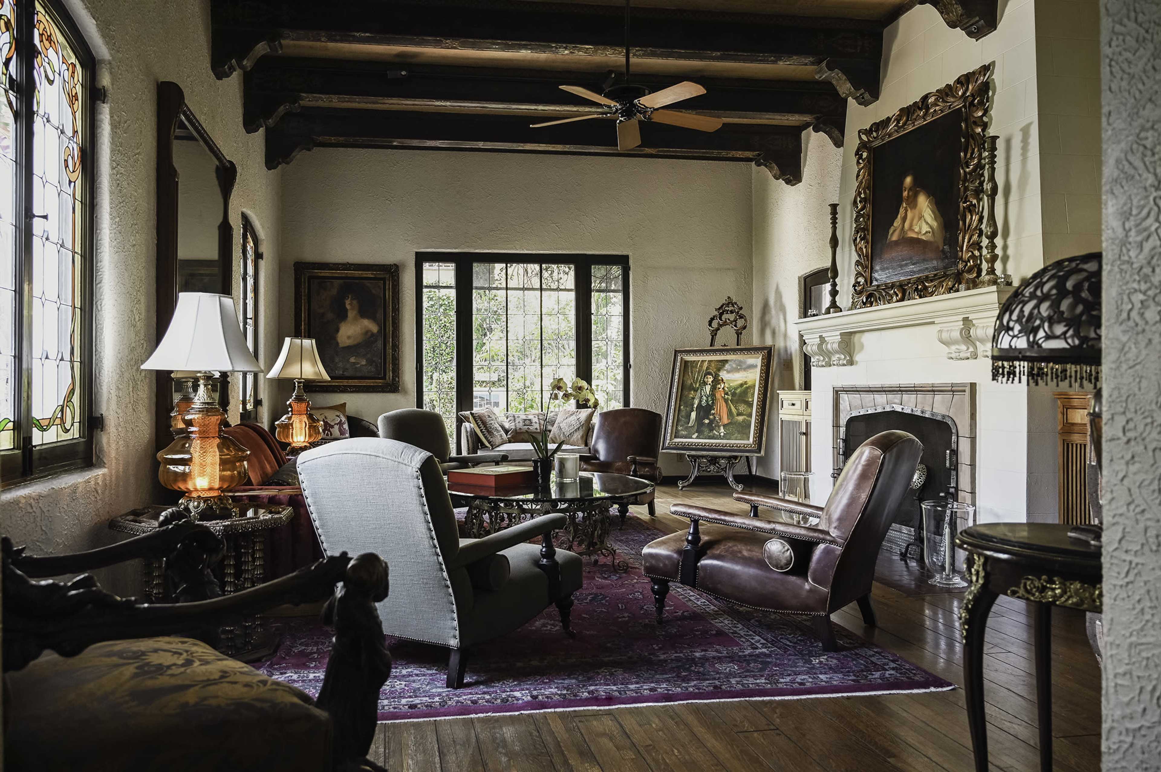 A stylish living room featuring vintage furniture, decorative artwork, and a large window that provides natural light.