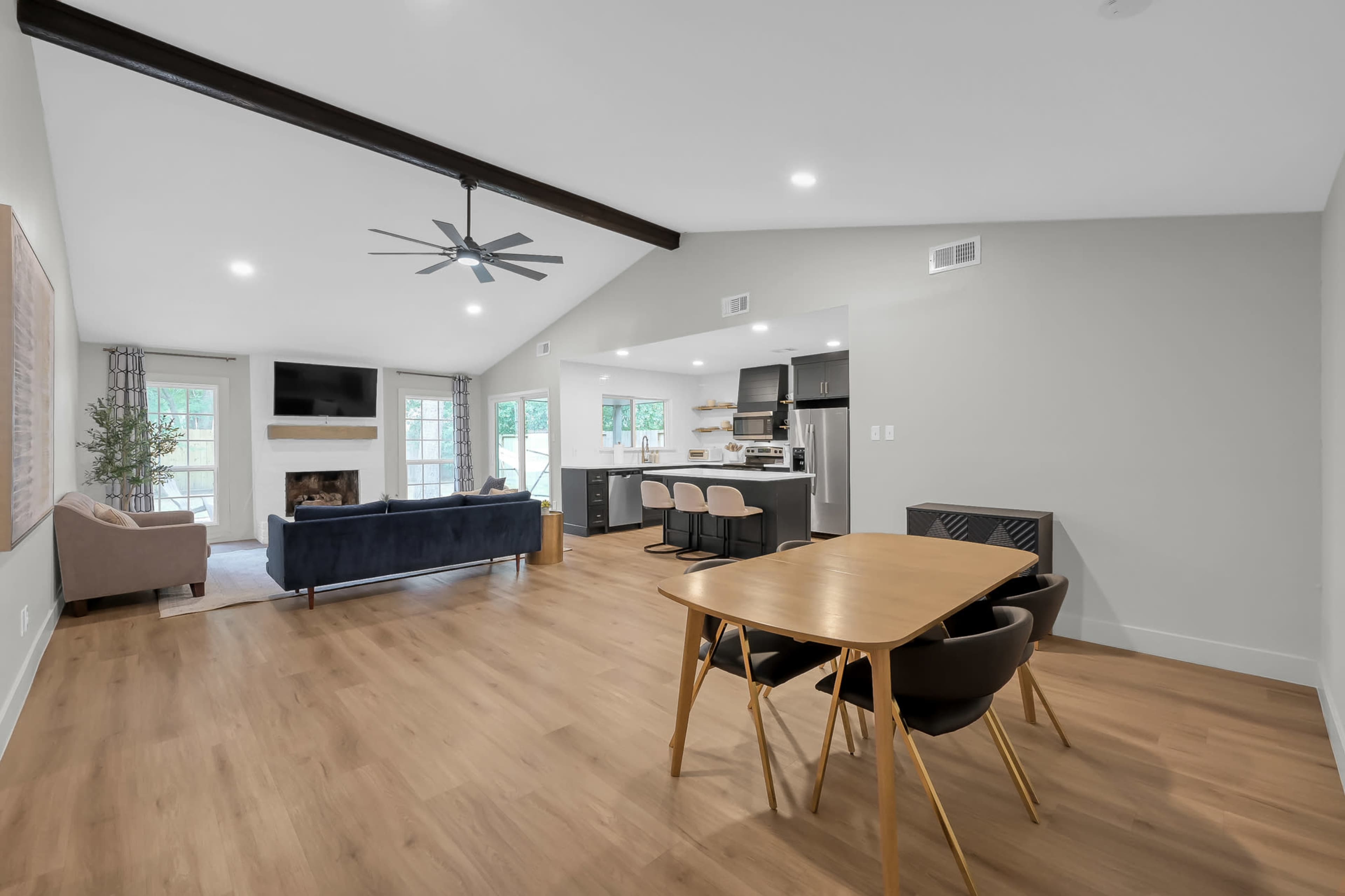 The image shows an open-concept living space that includes a dining area, a cozy seating area with a fireplace, and a modern kitchen.