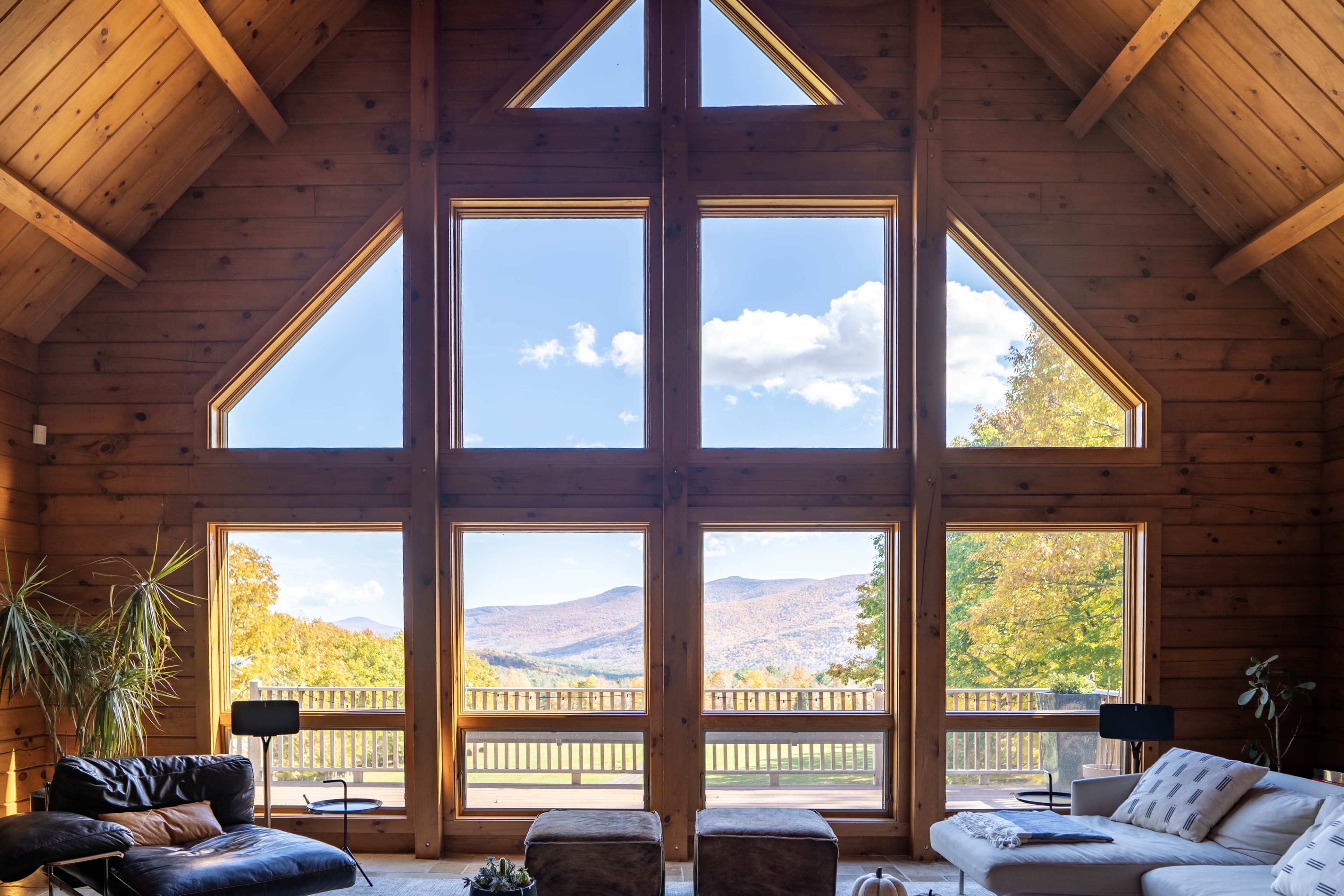 A spacious wooden cabin features large windows that frame a mountainous landscape.