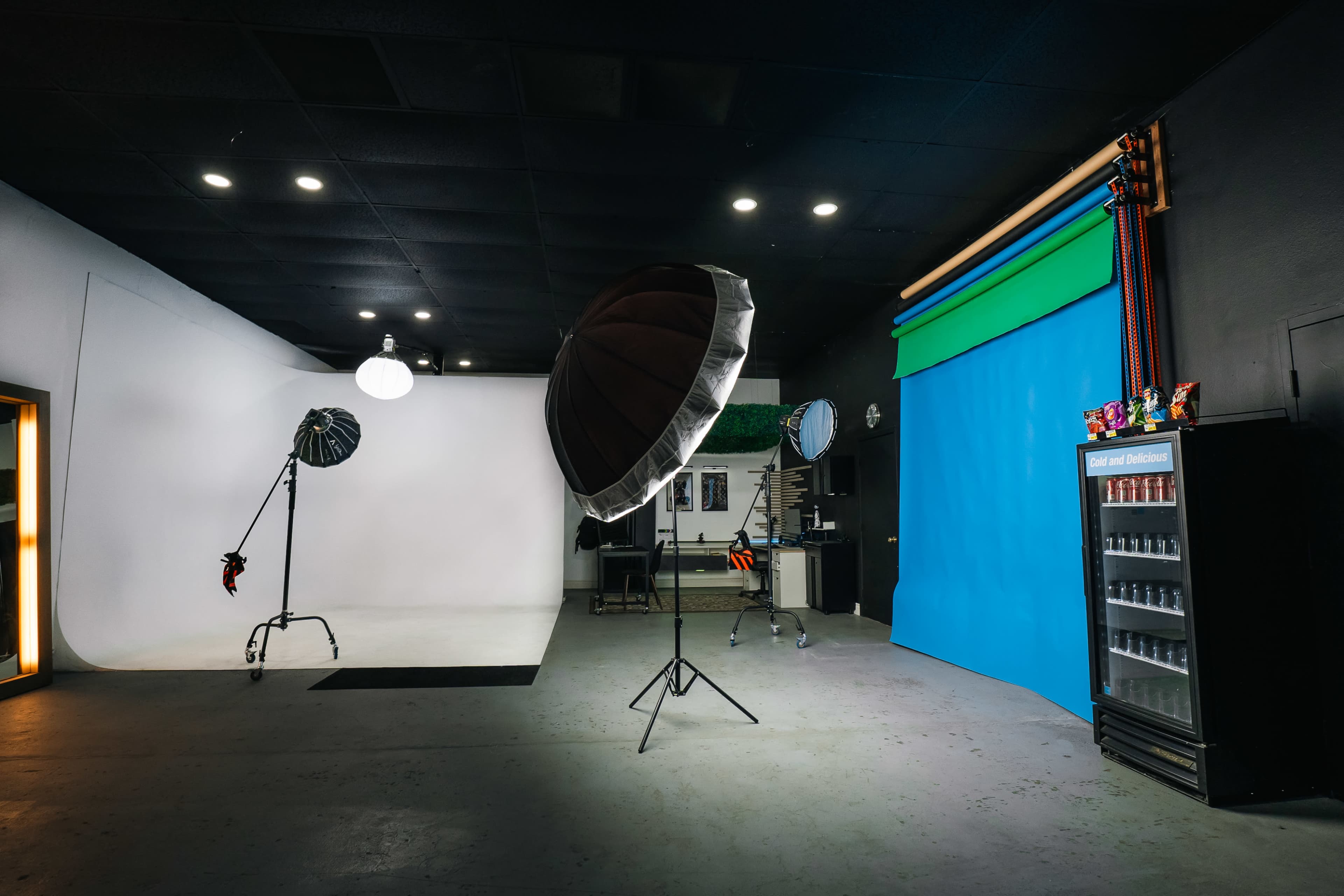 A photography studio with a white backdrop, a blue backdrop, lighting equipment, and a vending machine.