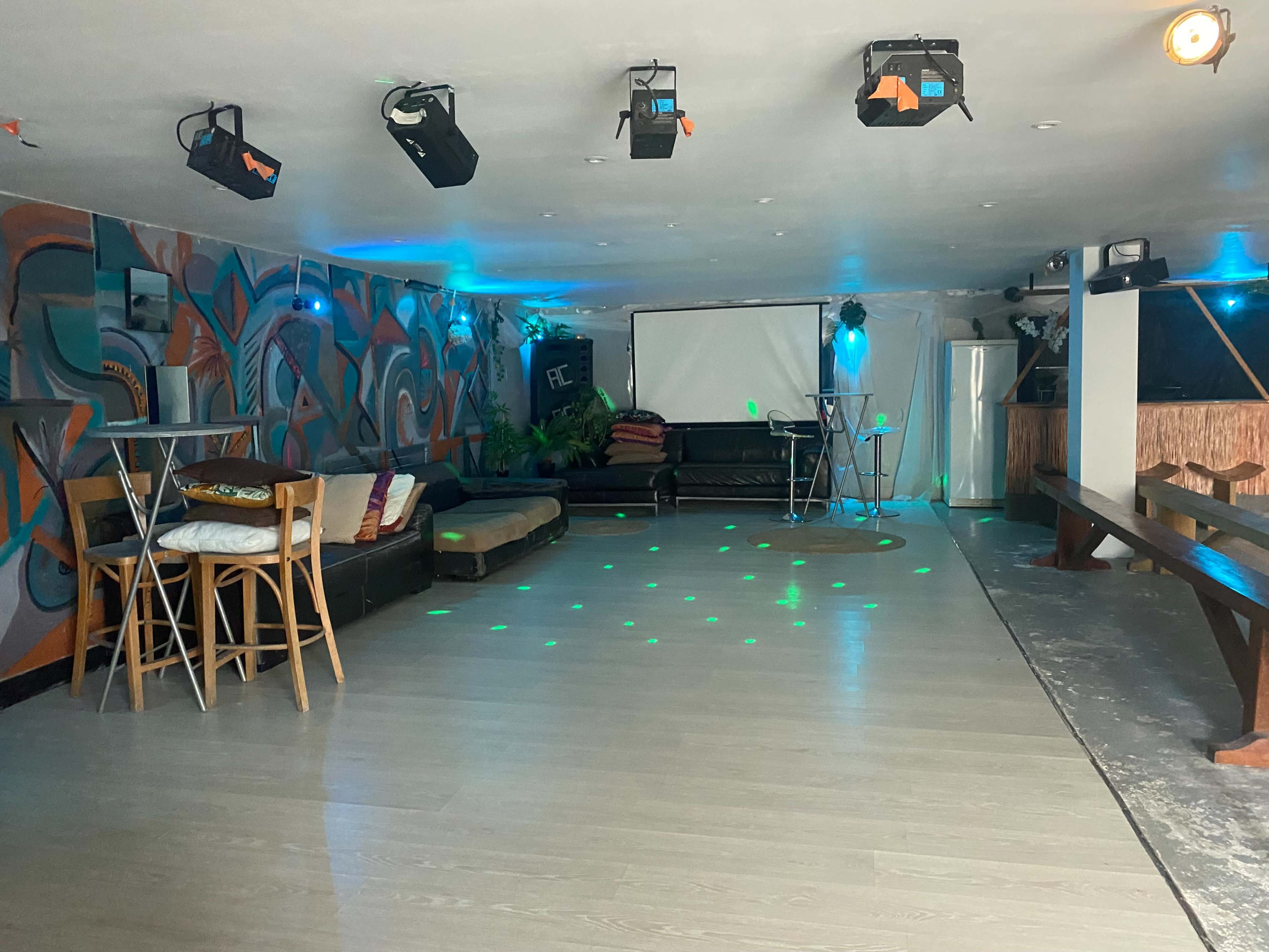 An empty lounge area with a dance floor, low seating, and colorful lighting.