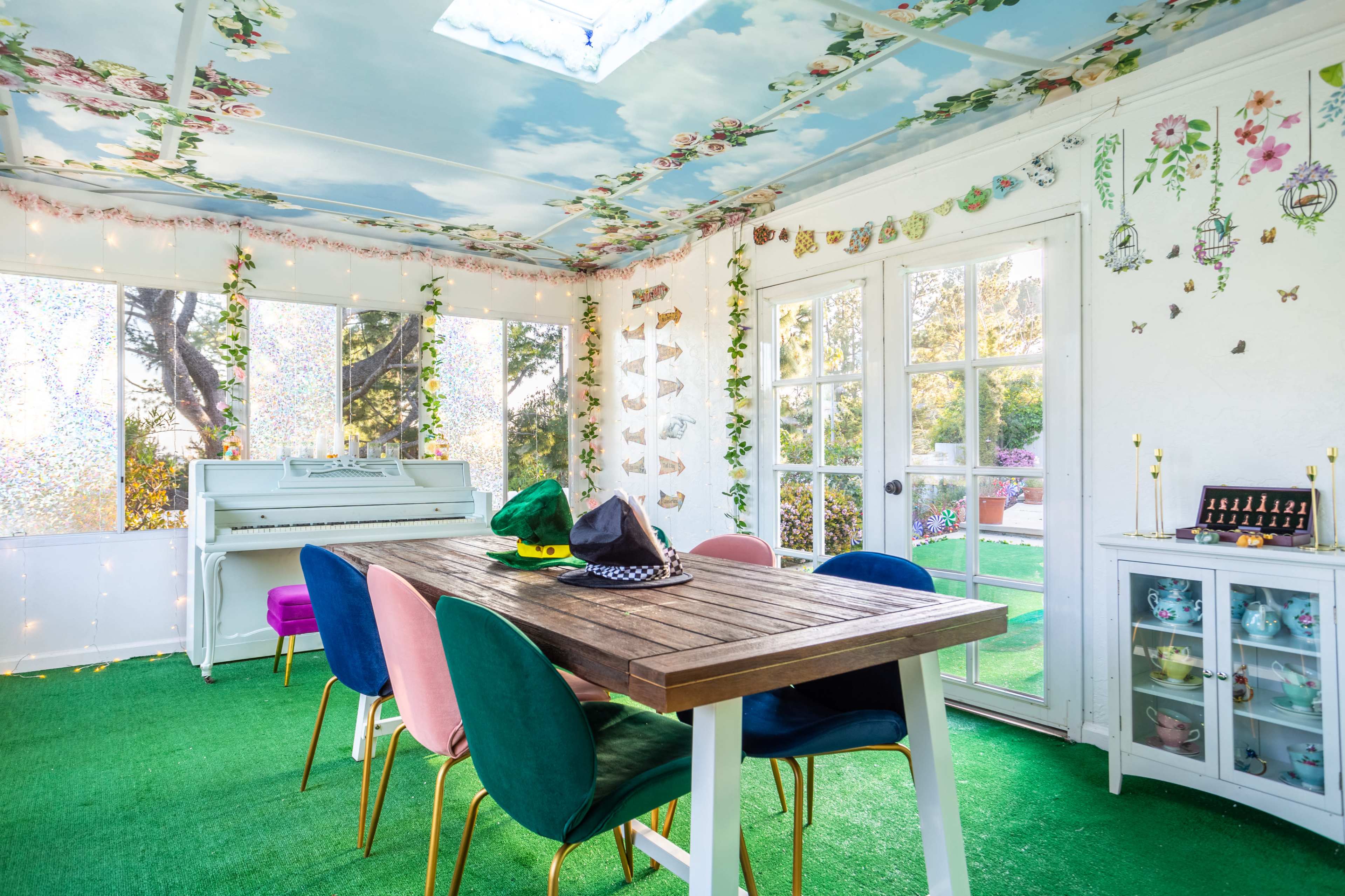 The room features a dining table surrounded by colorful chairs, a piano, and walls adorned with floral and butterfly decorations.