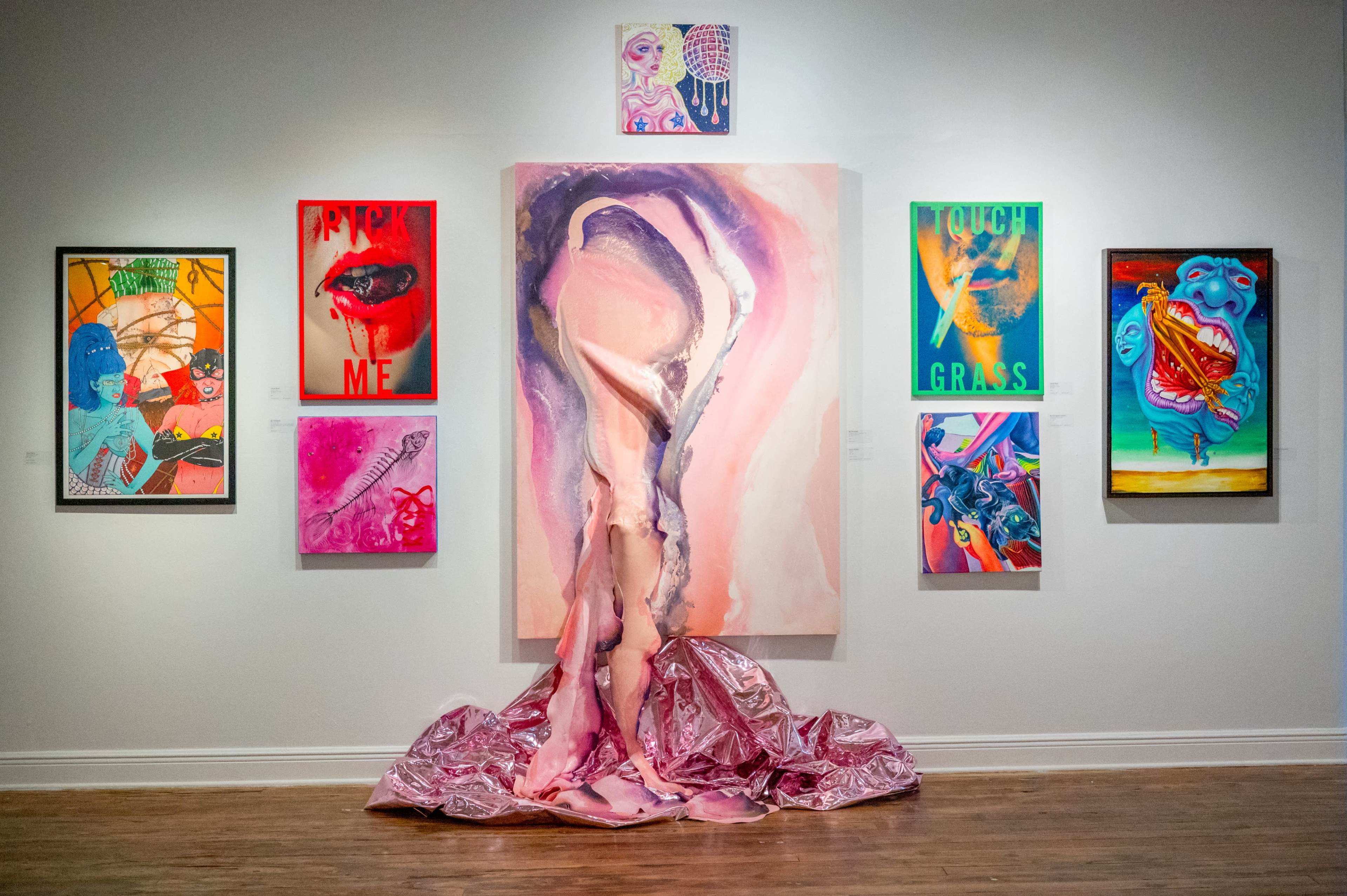 The image shows an art gallery featuring a central abstract painting with a draped fabric installation, surrounded by vibrant framed artworks on the walls.