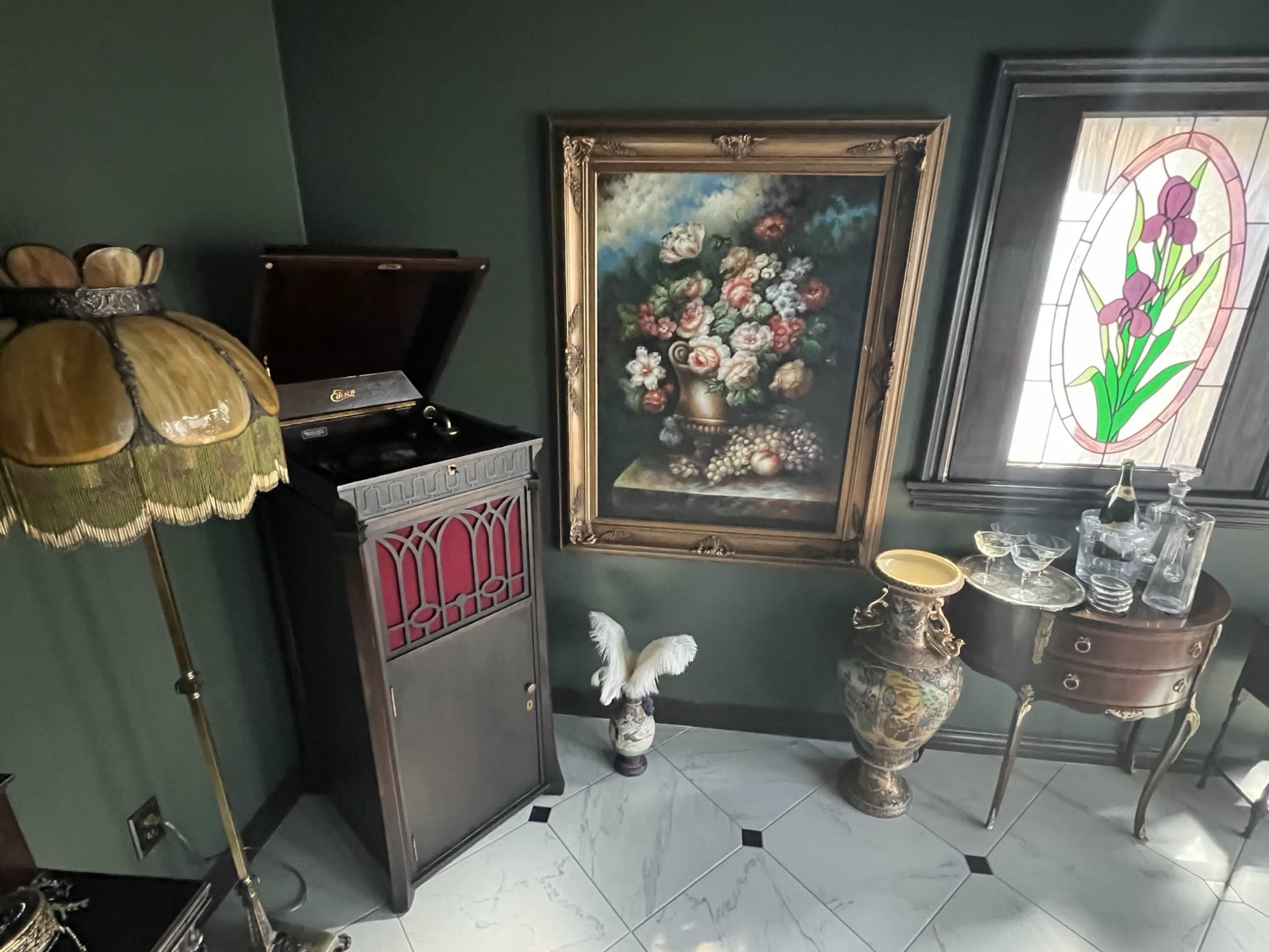 The image depicts a vintage room with a gramophone, a floral painting, a stained glass window, and various decorative objects, including a vase and a lamp.