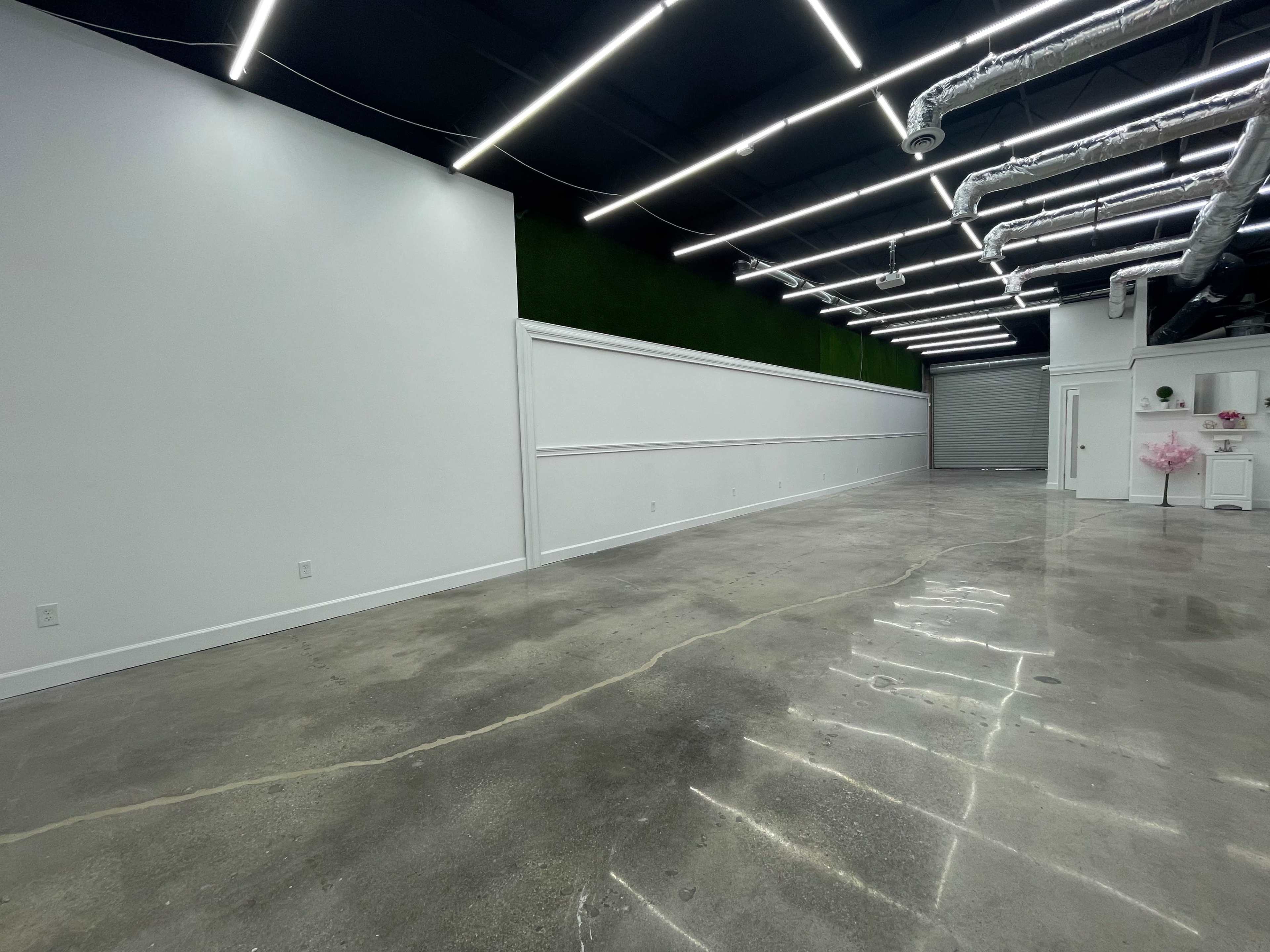 A spacious, minimally decorated interior with concrete floors and a white wall featuring decorative molding.