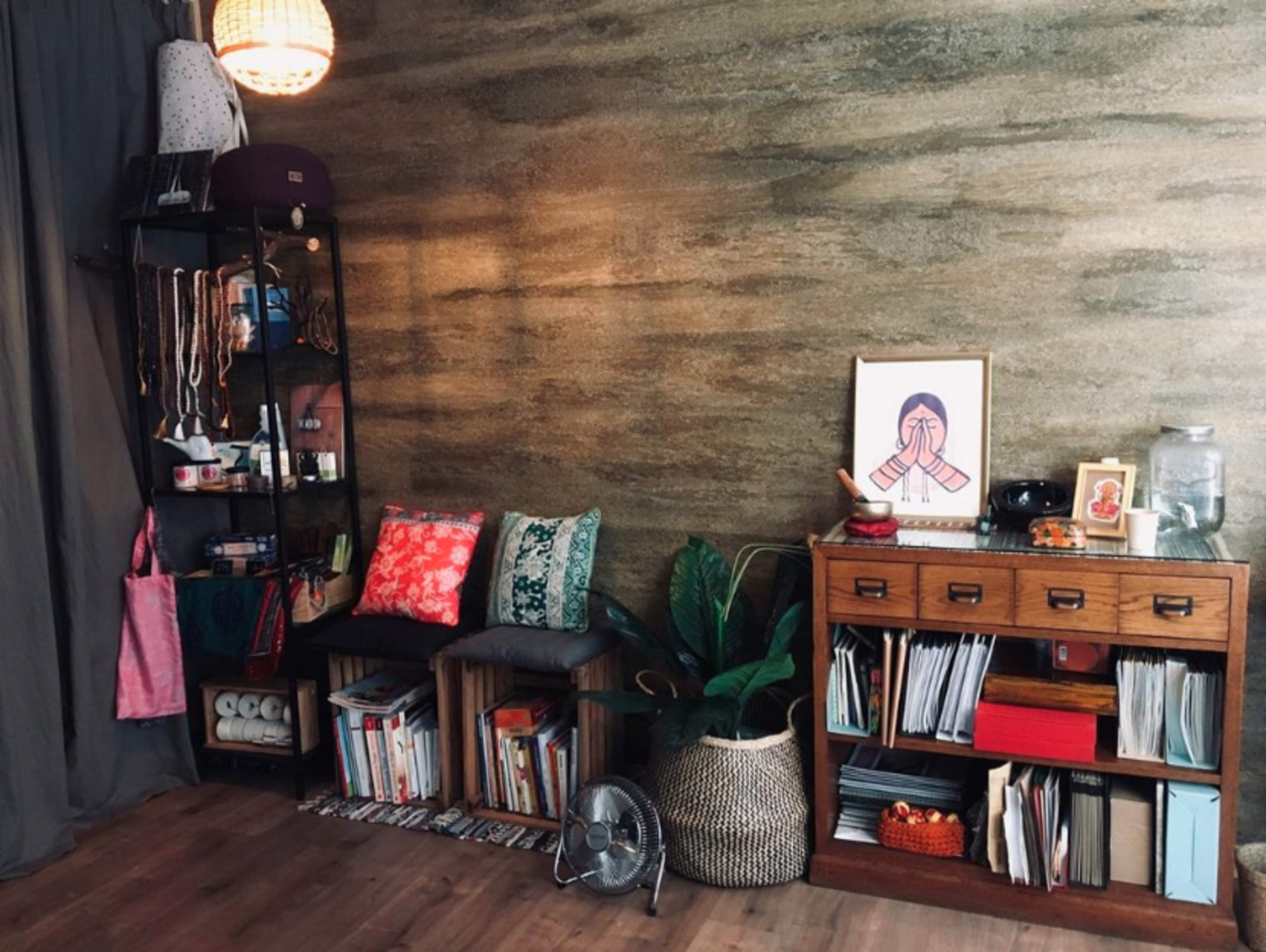 A cozy interior with a bookshelf, a potted plant, and a framed artwork against a textured wall.