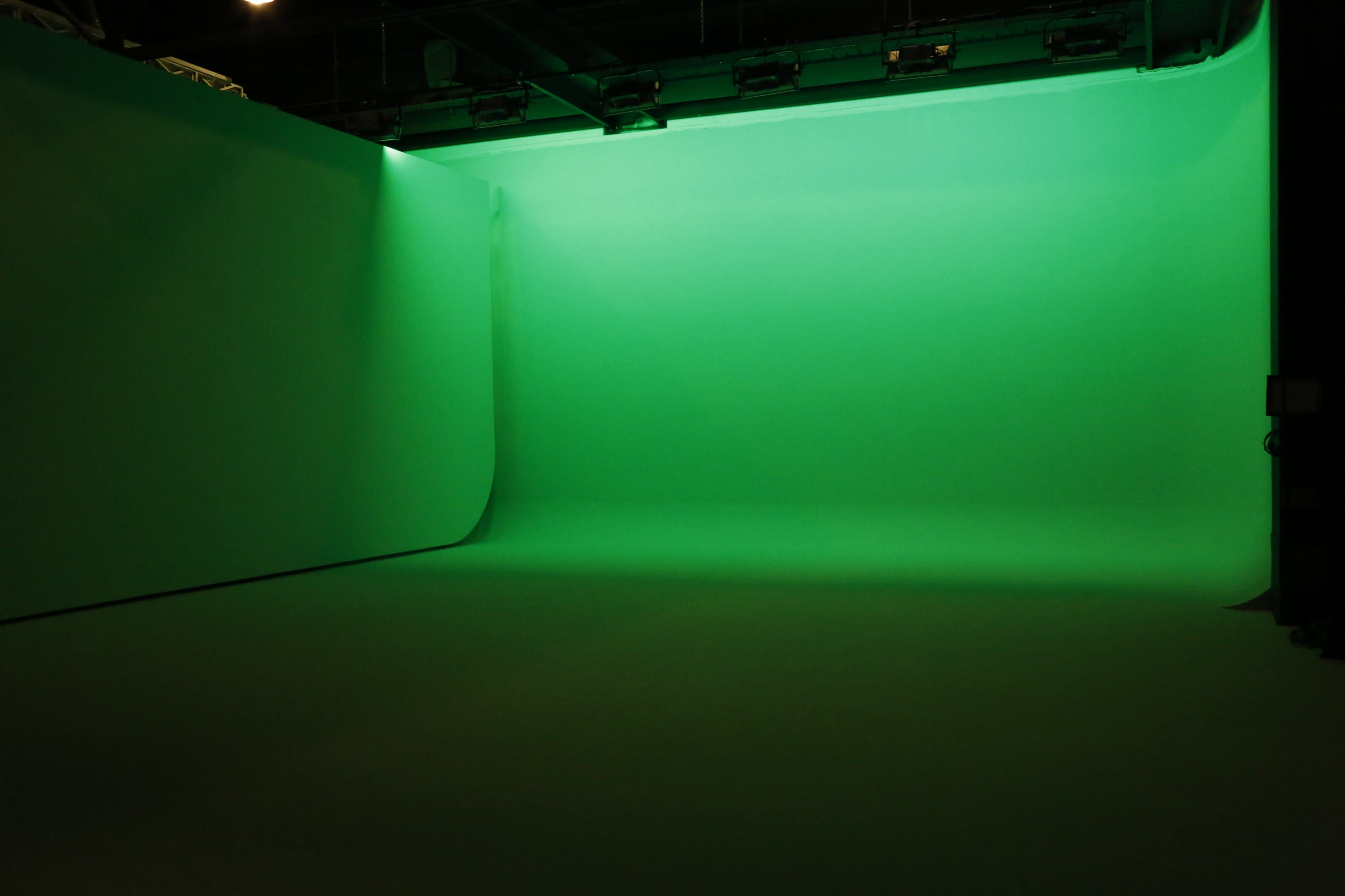 A green screen studio with evenly lit green walls and floor.