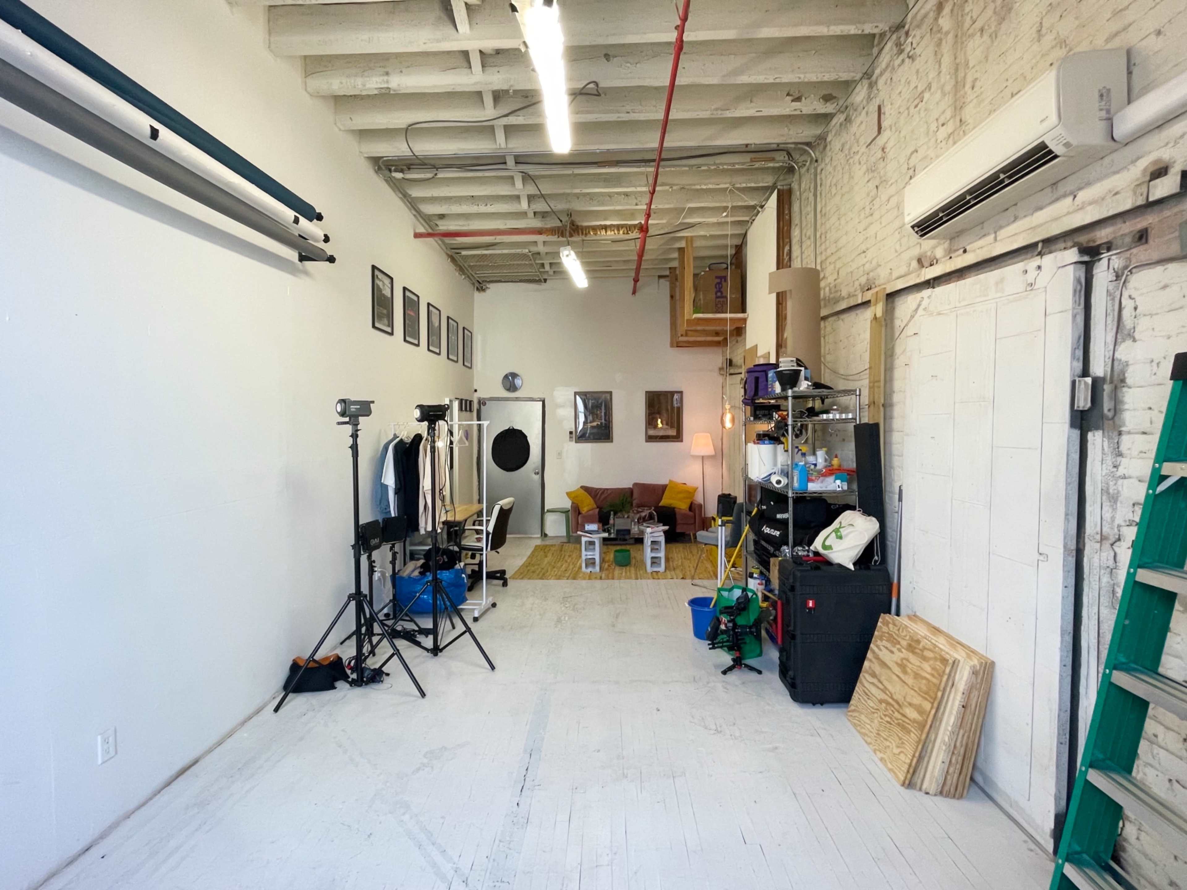 An empty studio space with various equipment, furniture, and materials arranged along the walls.