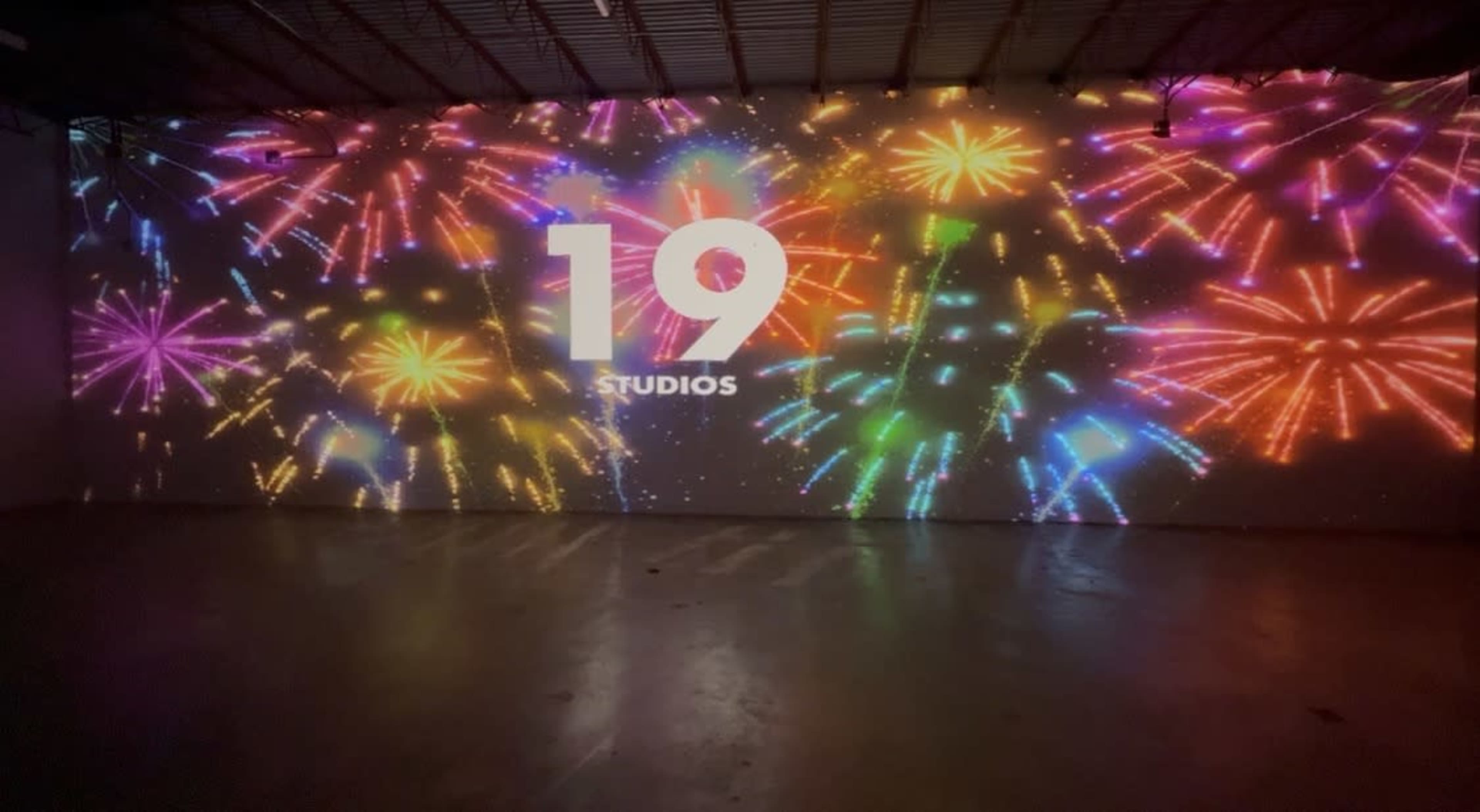 A large wall displays colorful fireworks graphics with the text "19 STUDIOS" in the center.