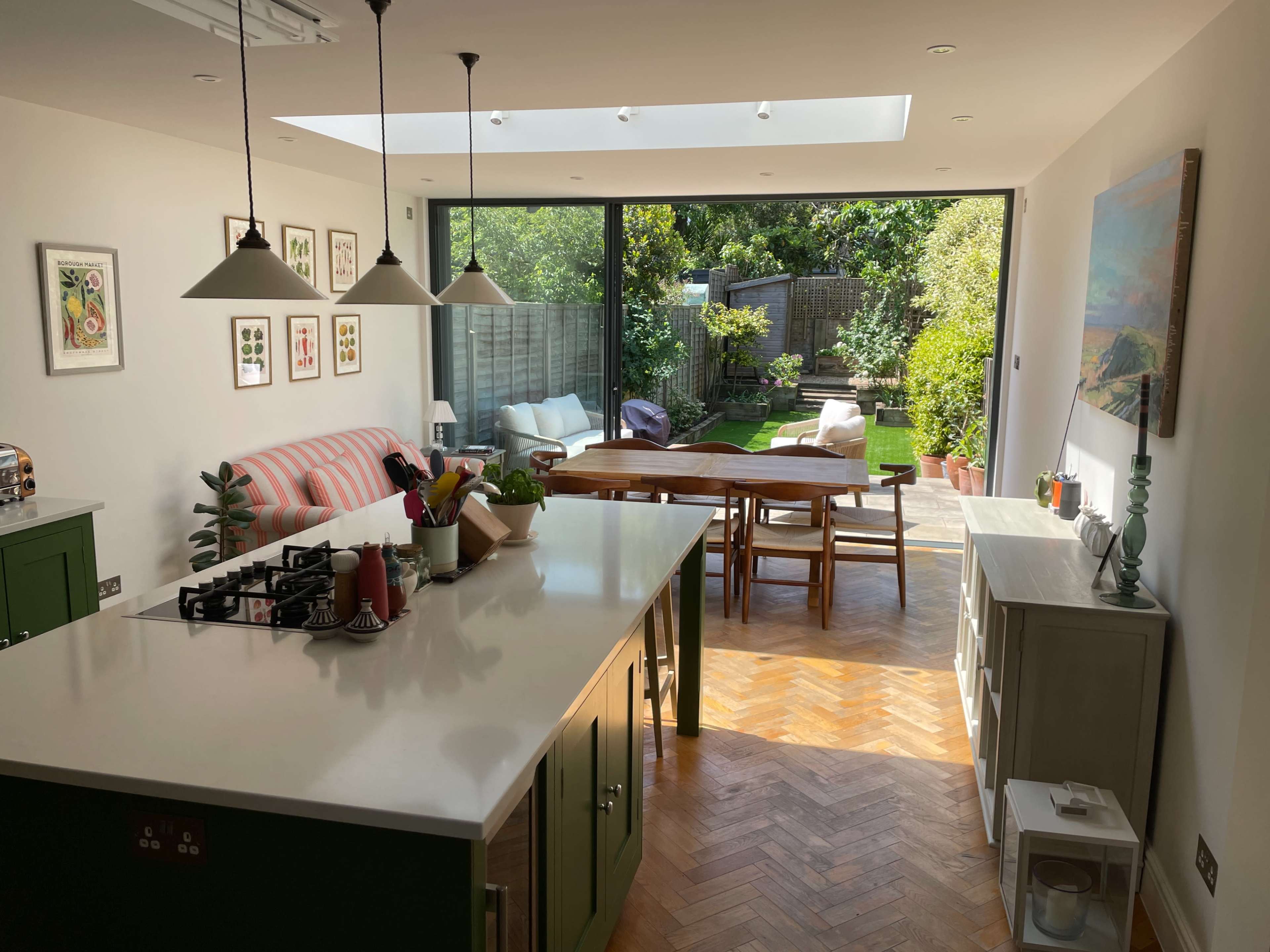 A modern kitchen with a large island opens to a well-maintained garden through sliding glass doors.
