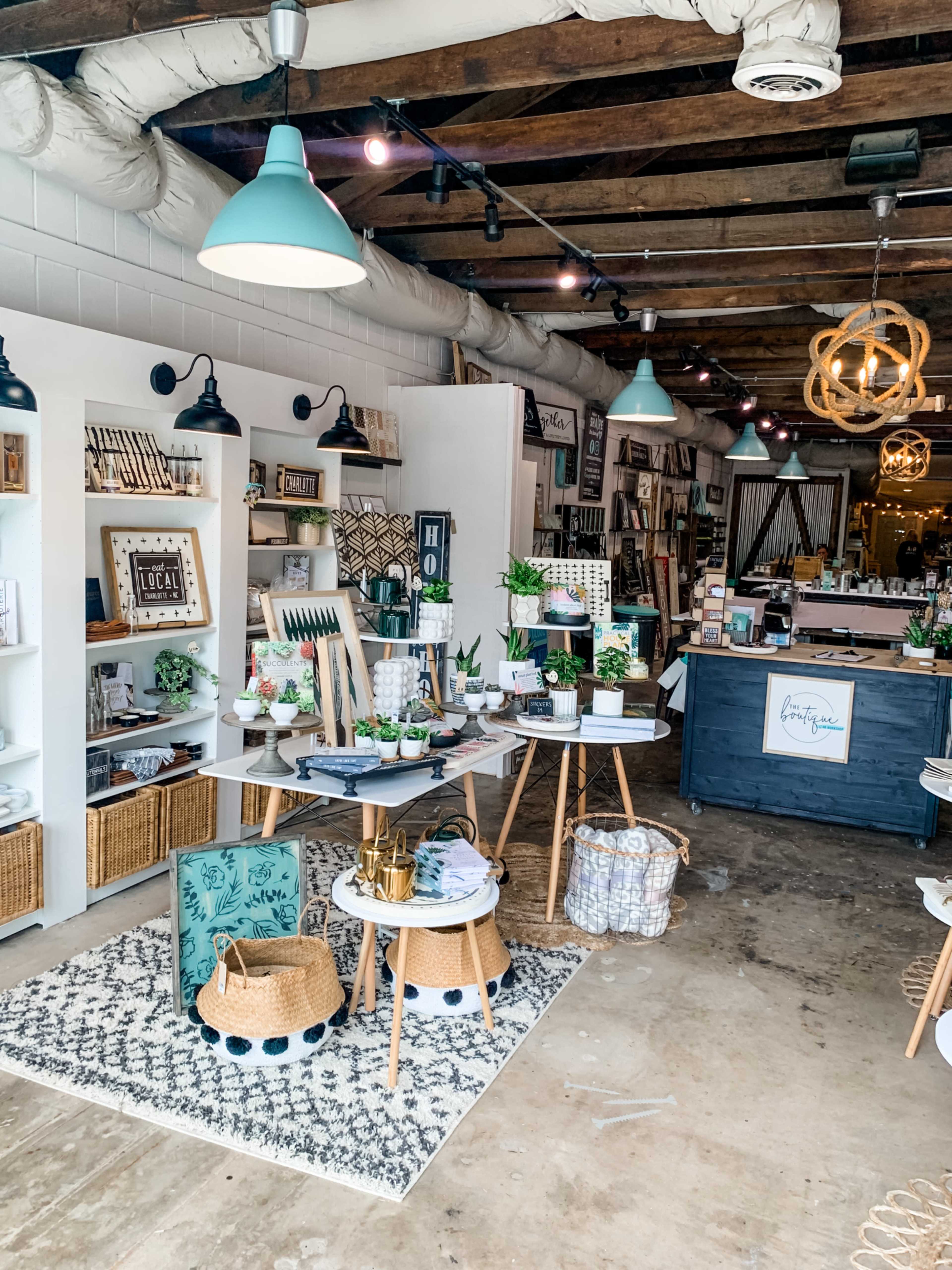 A retail shop features neatly arranged shelves with home decor items, tables displaying various products, and stylish lighting fixtures overhead.