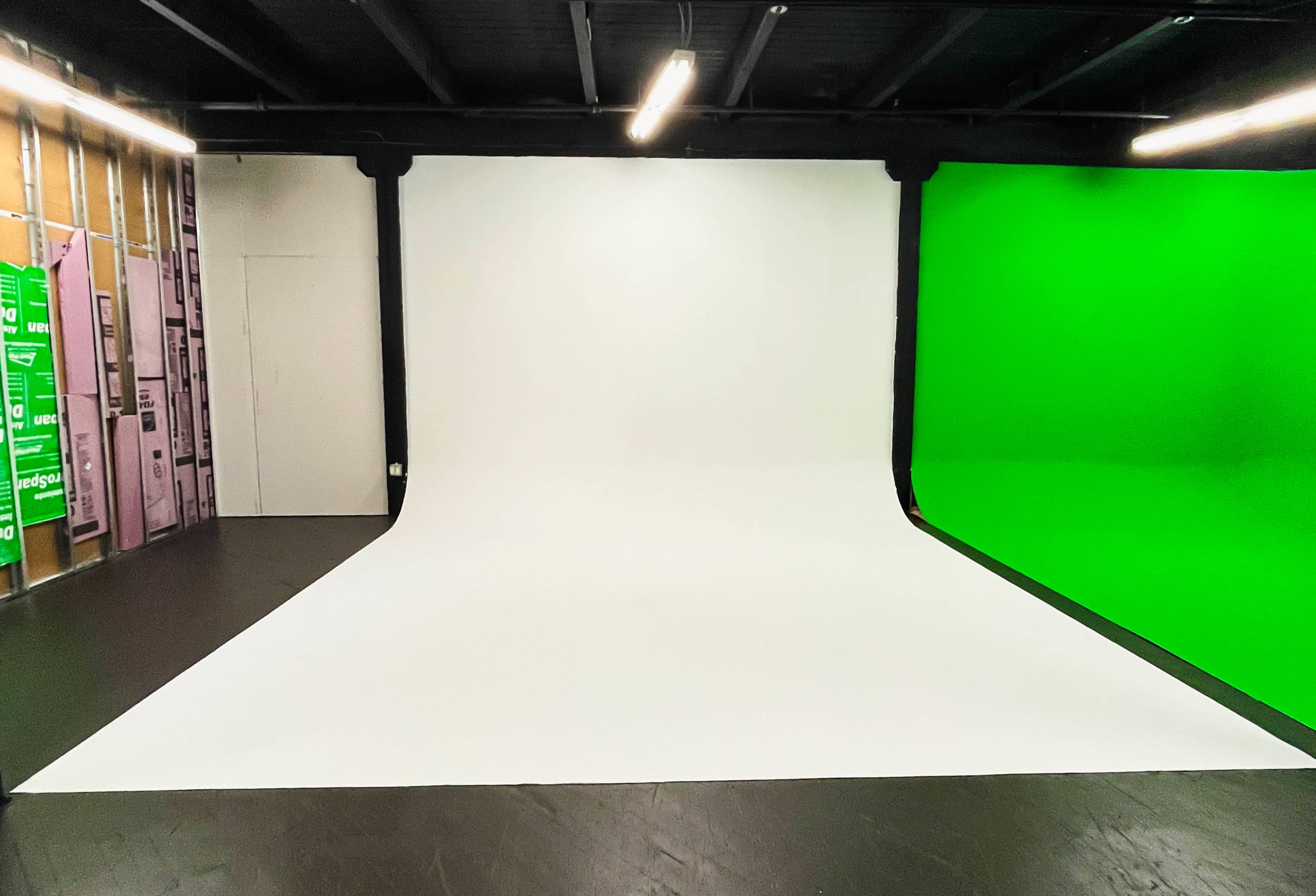 A photo studio with a white backdrop on the floor and a green backdrop on the right side.