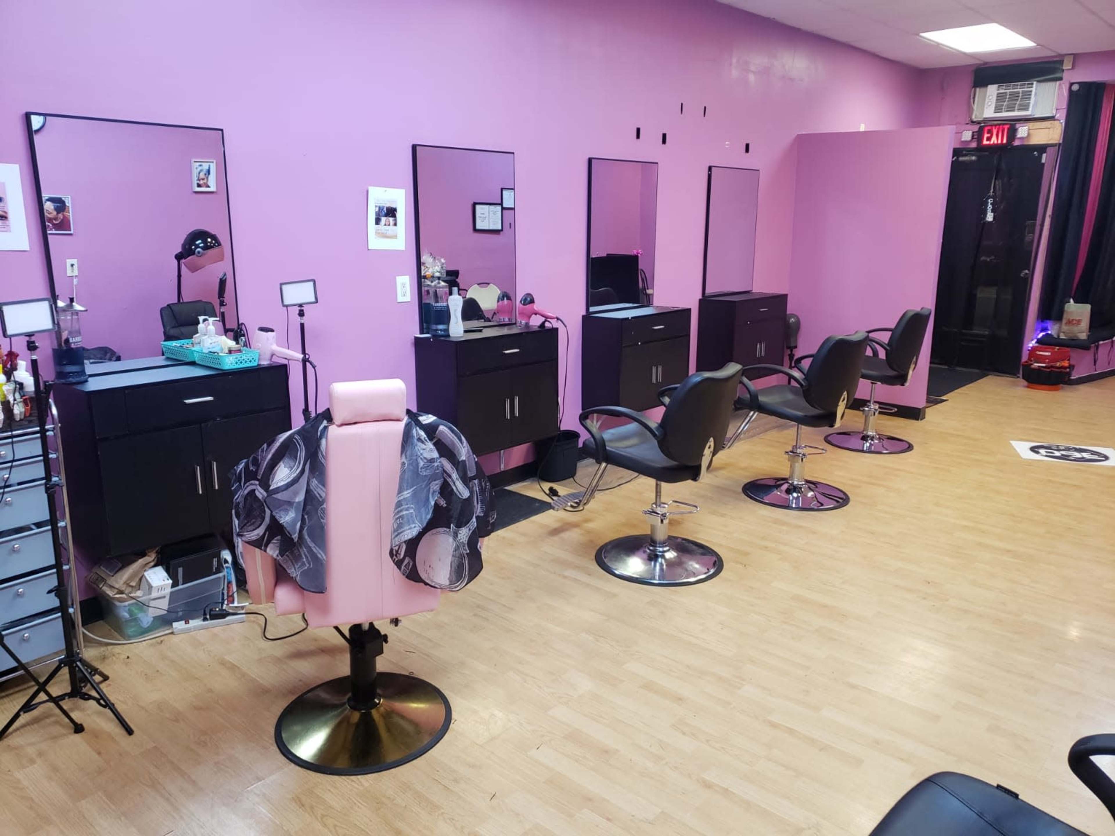 The image shows a hair salon with several stylist chairs, mirrors, and salon equipment against pink walls.