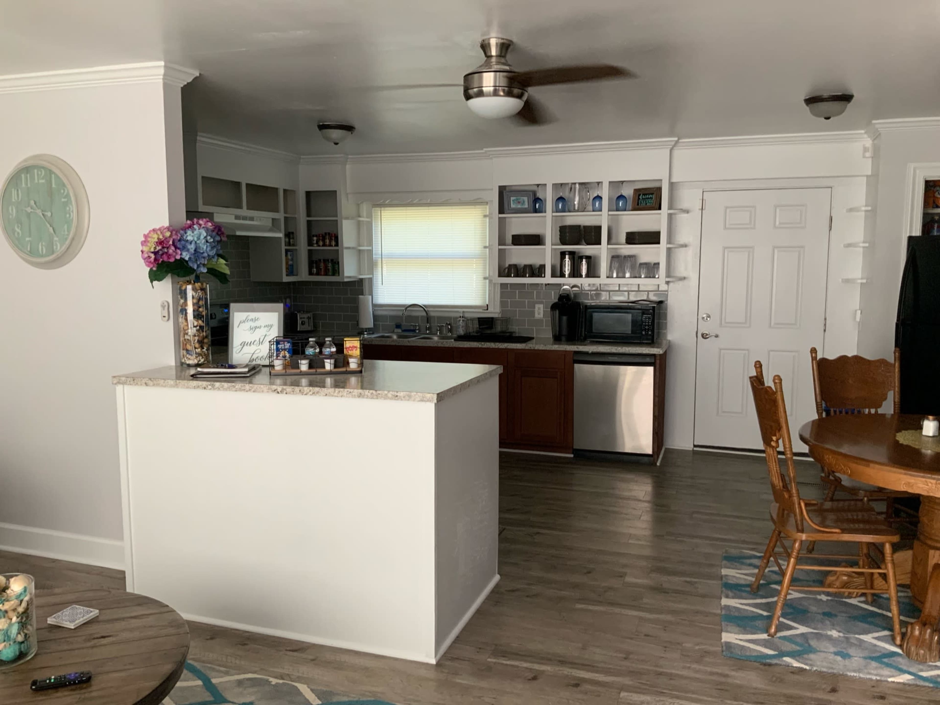 A modern kitchen with a central island, stainless steel appliances, wooden cabinets, and a dining area featuring a round table and chairs.