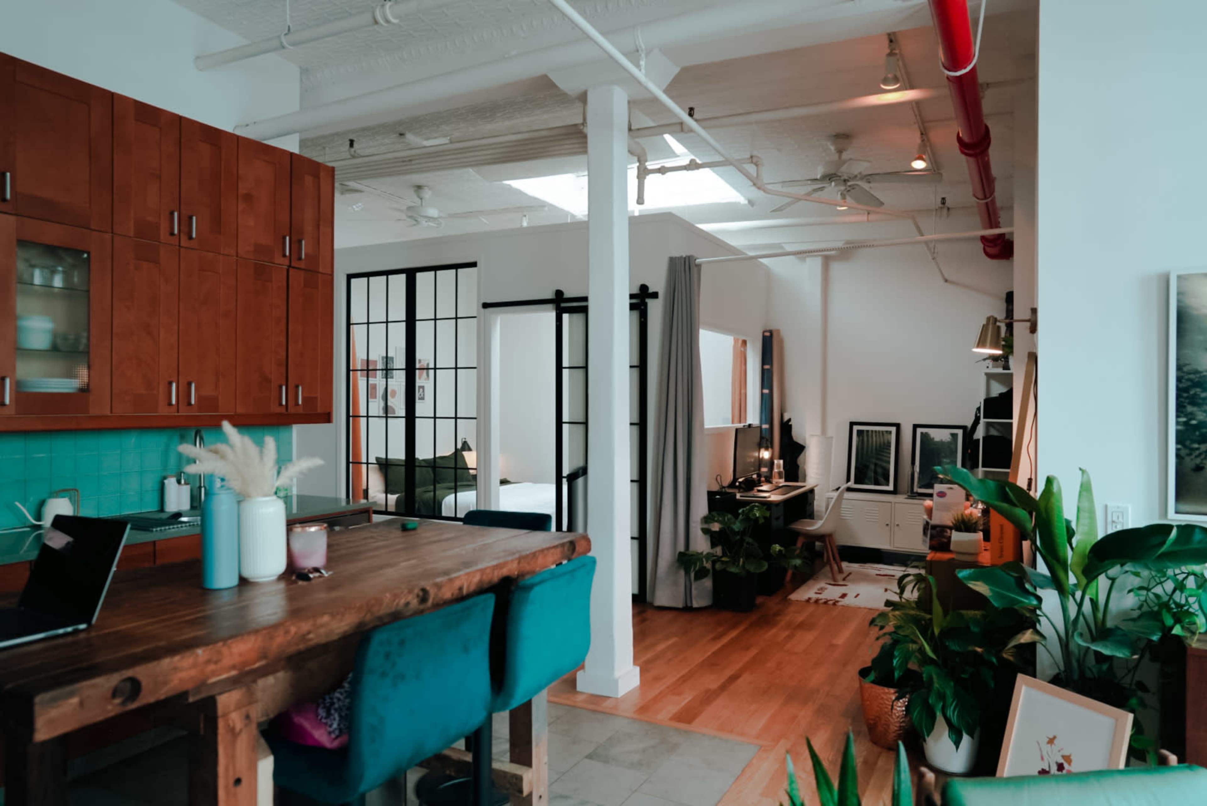 An open-concept living space featuring a kitchen area with wooden cabinets, a dining table, and a distinct separation for a bedroom through sliding doors.