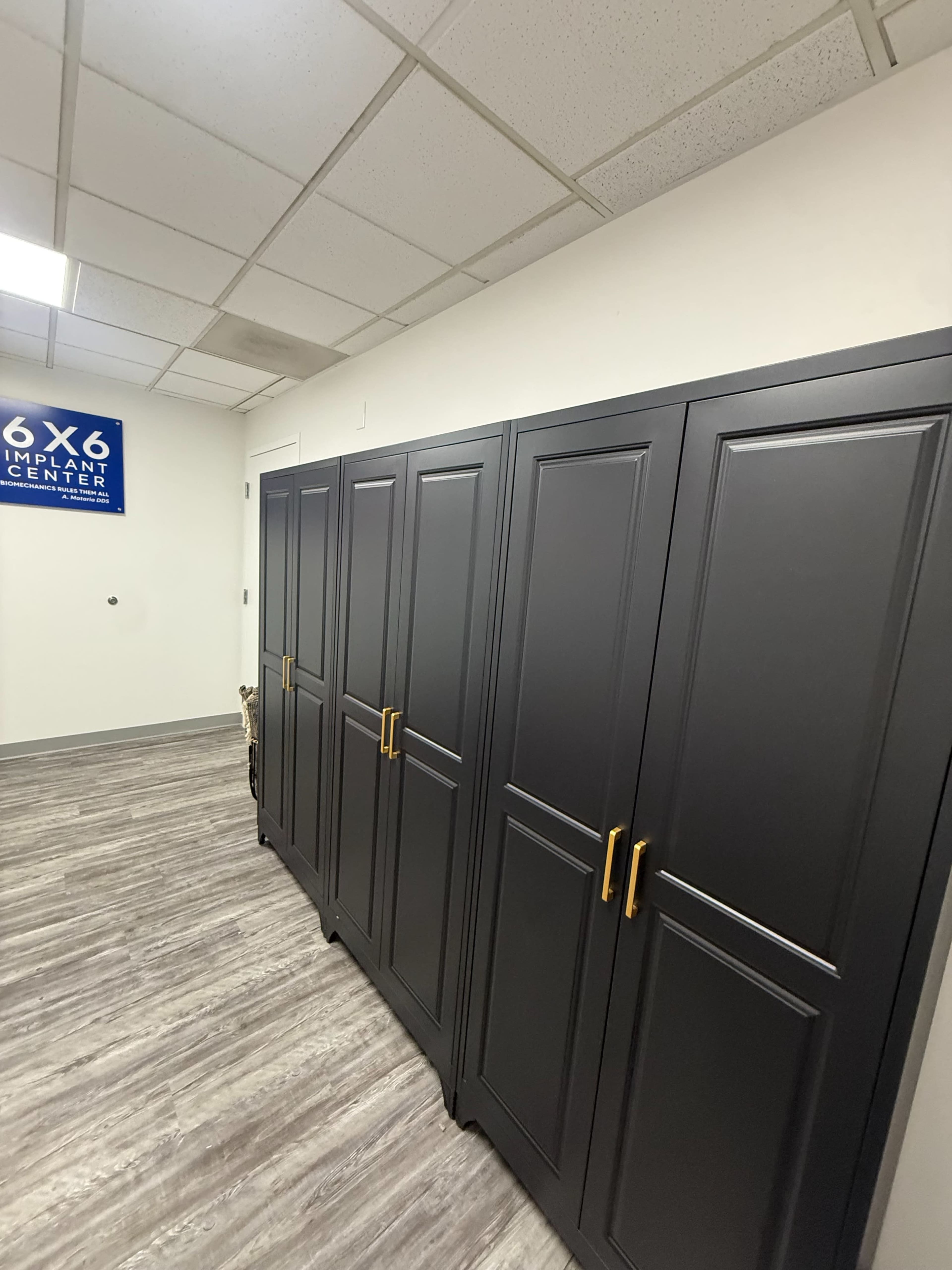 The image shows a hallway with several dark cabinets against the wall, and a sign for a dental implant center in the background.