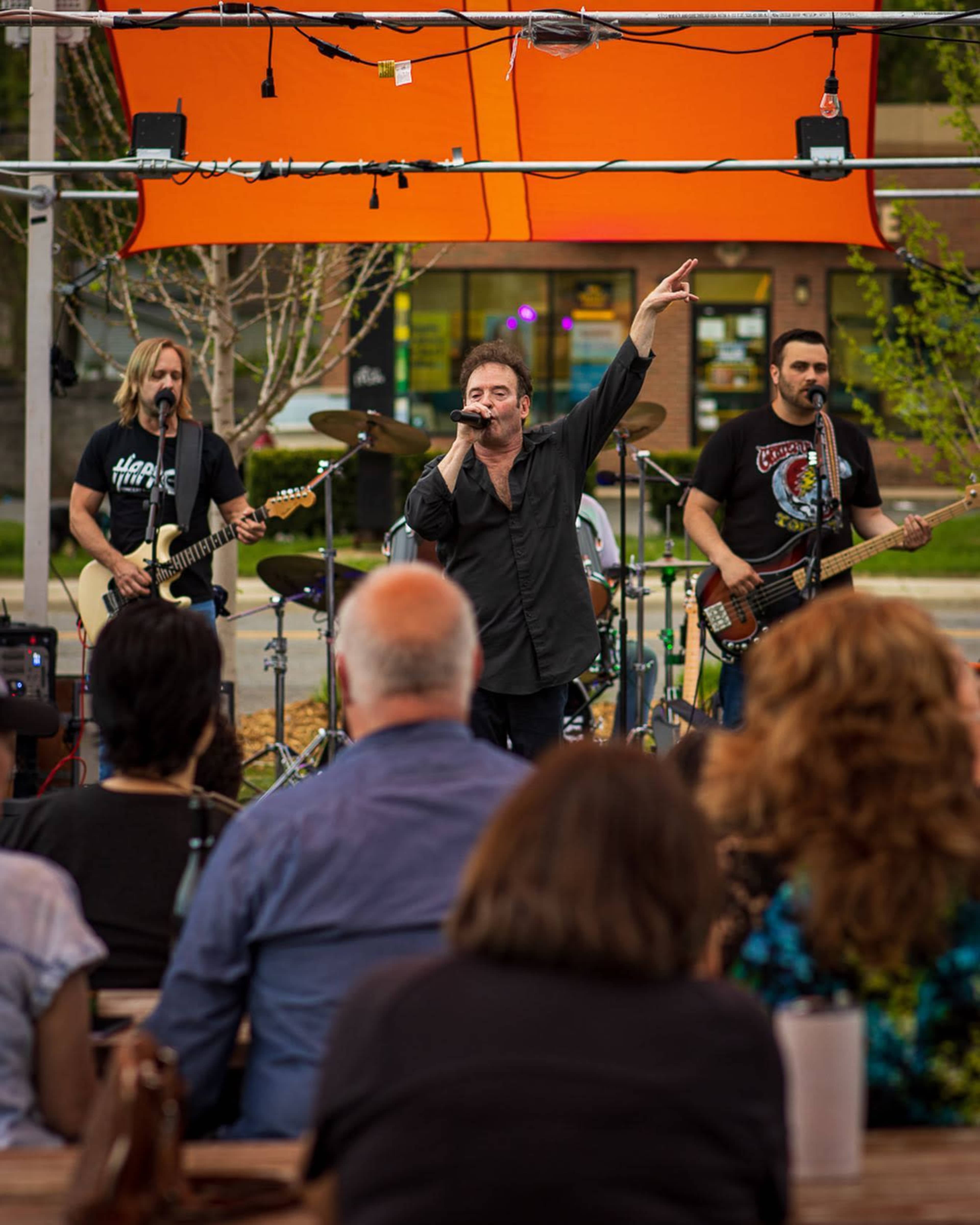 A live band performs on stage while an audience sits engaged in front of them.