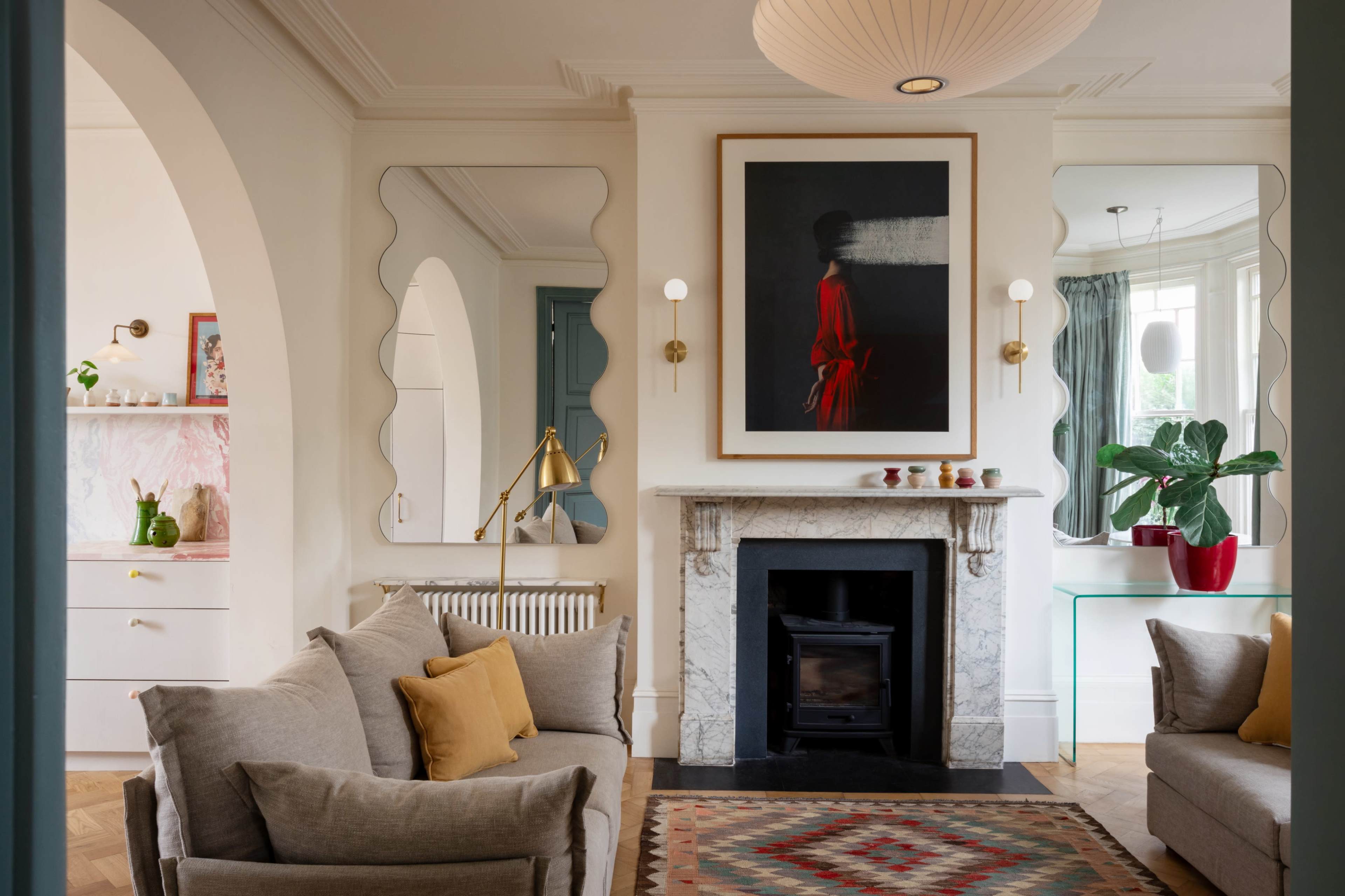 The image shows a stylish living room featuring a marble fireplace, comfortable sofas, and decorative elements like artwork and indoor plants.