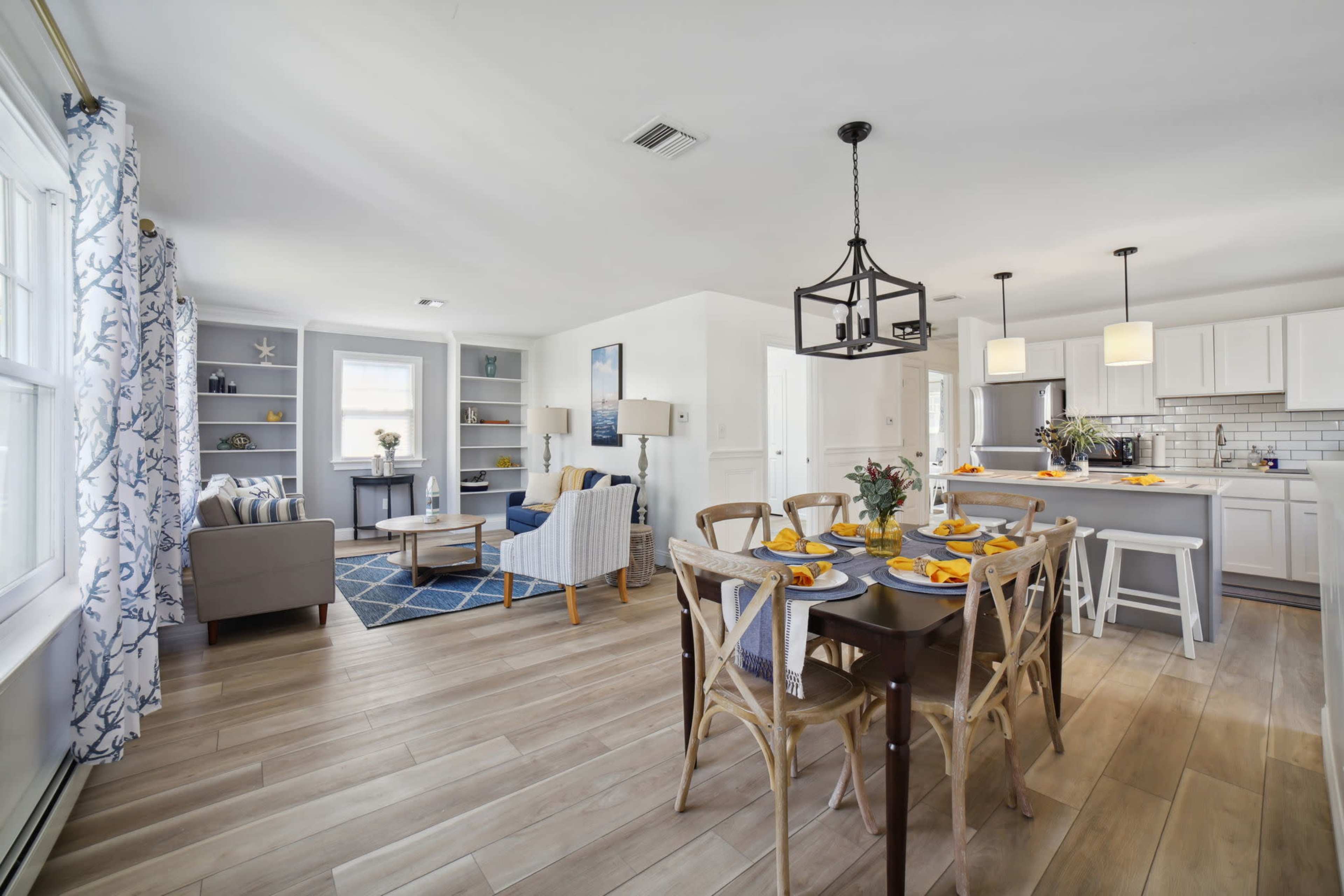 A light-filled open-concept living and dining area featuring a dining table set for breakfast, a cozy seating arrangement, and a modern kitchen.