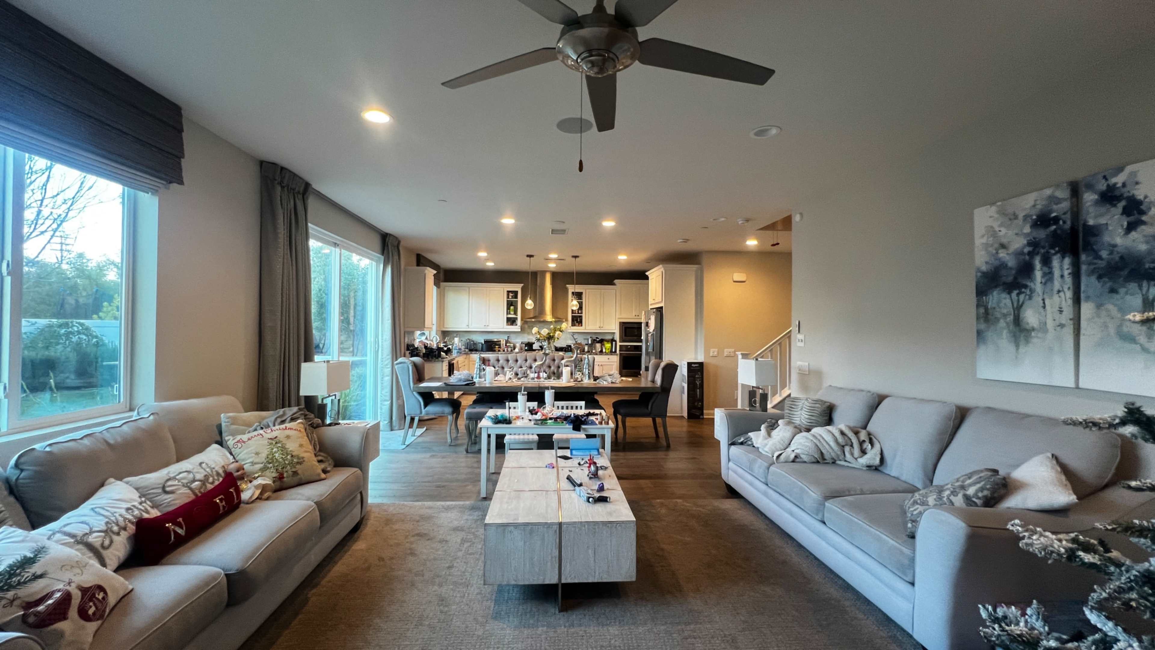 A spacious living room features two sofas, a coffee table, and a dining area with a modern kitchen in the background.