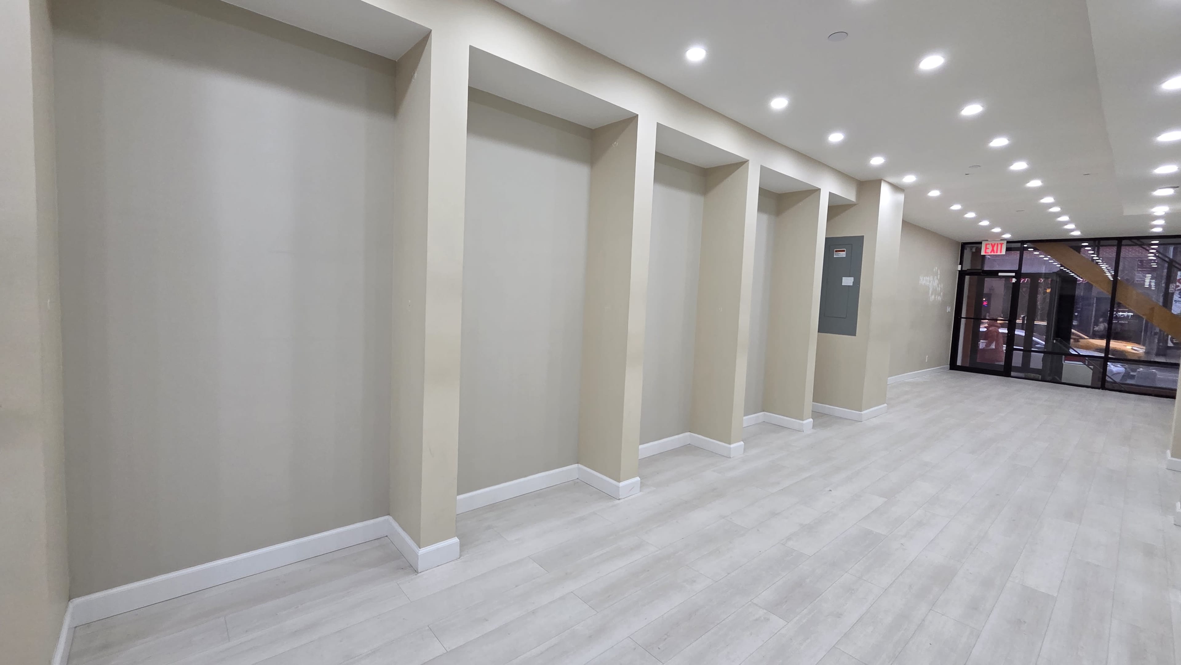 The image shows a well-lit hallway featuring five recessed wall niches along one side, with a glass entrance at the far end.